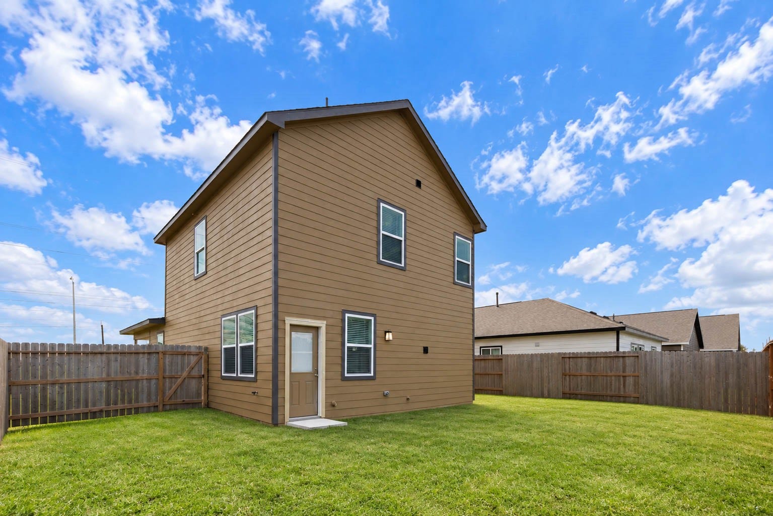 1115 Santee Court, Rosharon, TX 77583 The back of the home shows durable lap siding in a warm brown tone, a back door with a concrete stoop and a long, level lawn bordered by a wood privacy fence. There is plenty of room for a patio, garden or play area, and the fence helps keep pets and kids safely in the yard. Windows on both levels bring in light.