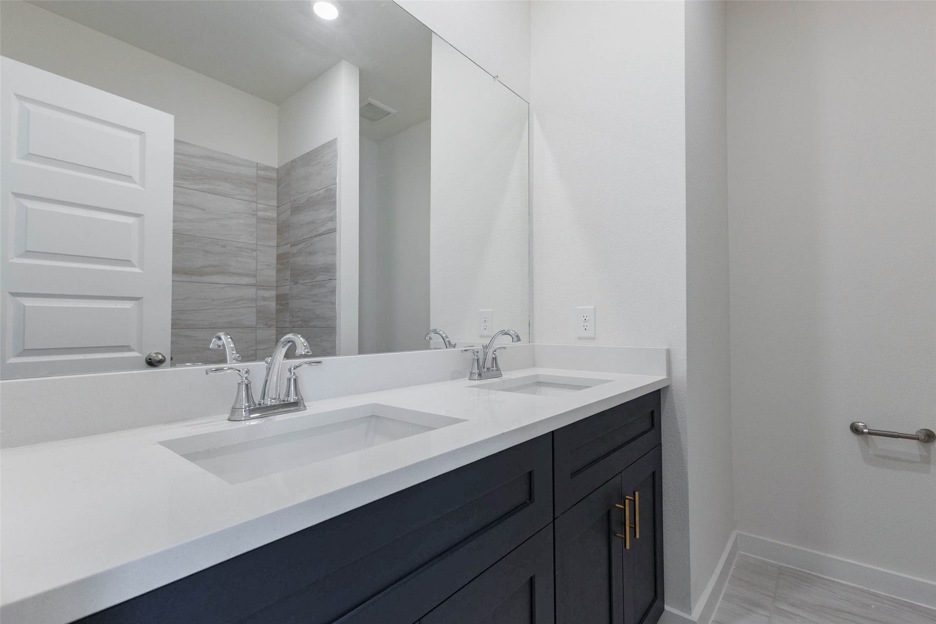 1115 Santee Court, Rosharon, TX 77583 The shared bath features a double-sink navy vanity with a white countertop, polished chrome faucets and a large mirror, so two people can get ready at the same time. The cabinet pulls match the gold hardware in the kitchen, tying the design together. Tile flooring is durable and easy to clean, and the tub-shower combination keeps the layout practical for the whole household.