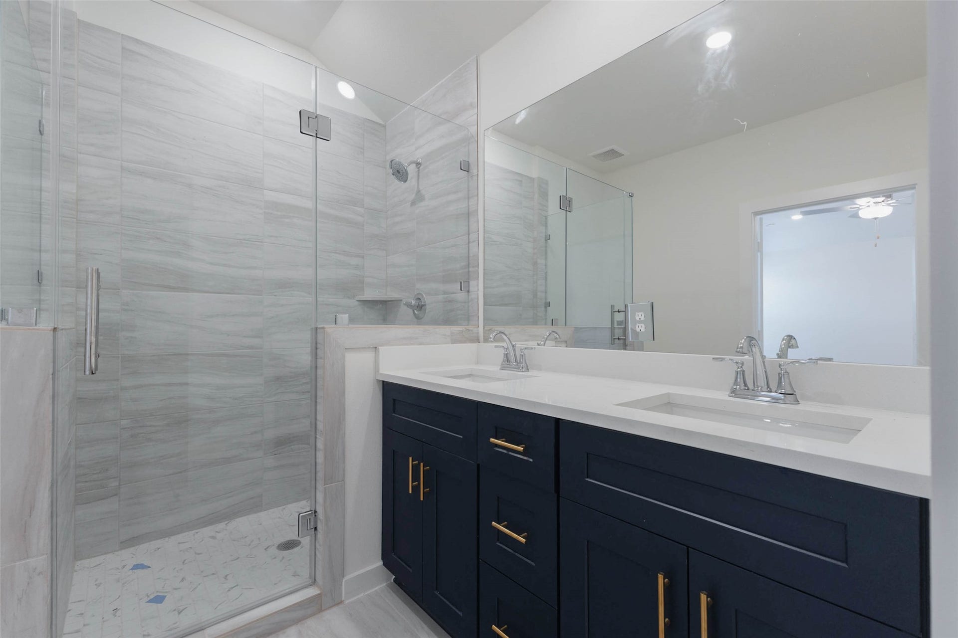 1115 Santee Court, Rosharon, TX 77583 Here the glass-enclosed shower shows off a pebble-style floor, a corner shelf and a rain-style shower head, designed to feel like a spa at home. The double-sink vanity offers great storage, and the large mirror reflects natural light from the window. Quality finishes and thoughtful details make this a luxurious retreat after a long day at work.