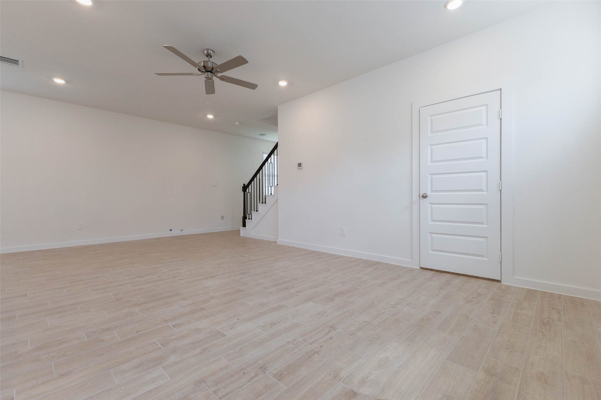 1115 Santee Court, Rosharon, TX 77583 Another angle of the main living space shows a ceiling fan, a closet door for coat or cleaning storage and the staircase tucked in the corner. The wood-look floors are easy to clean and sturdy for kids and pets, and the neutral walls pair with any decor. There is plenty of space to define a seating area and a dining area without feeling crowded.