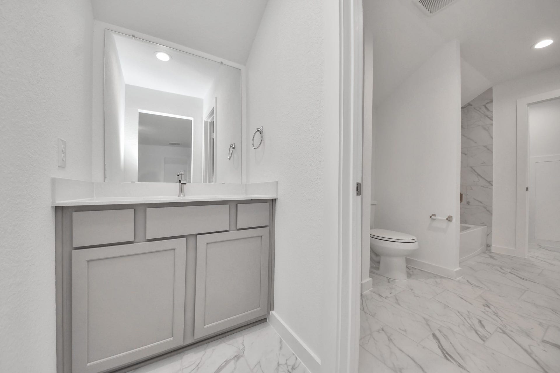 1017 Golden Glow Path, Magnolia, TX 77355 Experience convenience in the secondary bathroom, designed for Jack and Jill arrangements, now with a separate vanity area. This well-appointed space showcases stylish tile flooring, a bath/shower combo with an elegant tile surround, and light-stained wood cabinets. The beautiful light countertop adds a touch of sophistication, combining functionality and aesthetics seamlessly.