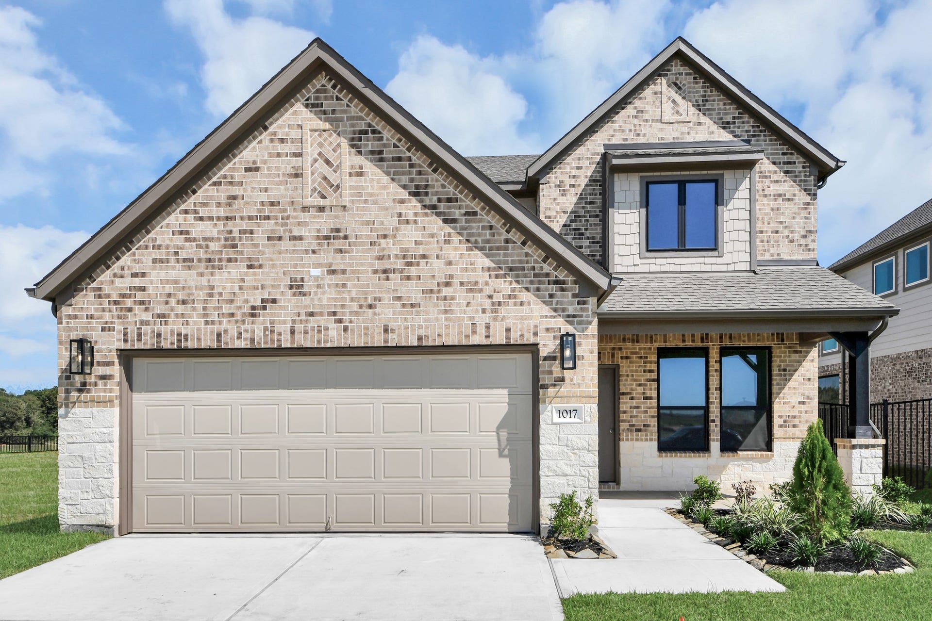 1017 Golden Glow Path, Magnolia, TX 77355 Meticulously maintained yard and lush landscape, paired with a premium elevation featuring captivating brick accents. Modern coach lights add a touch of contemporary elegance to the exterior.