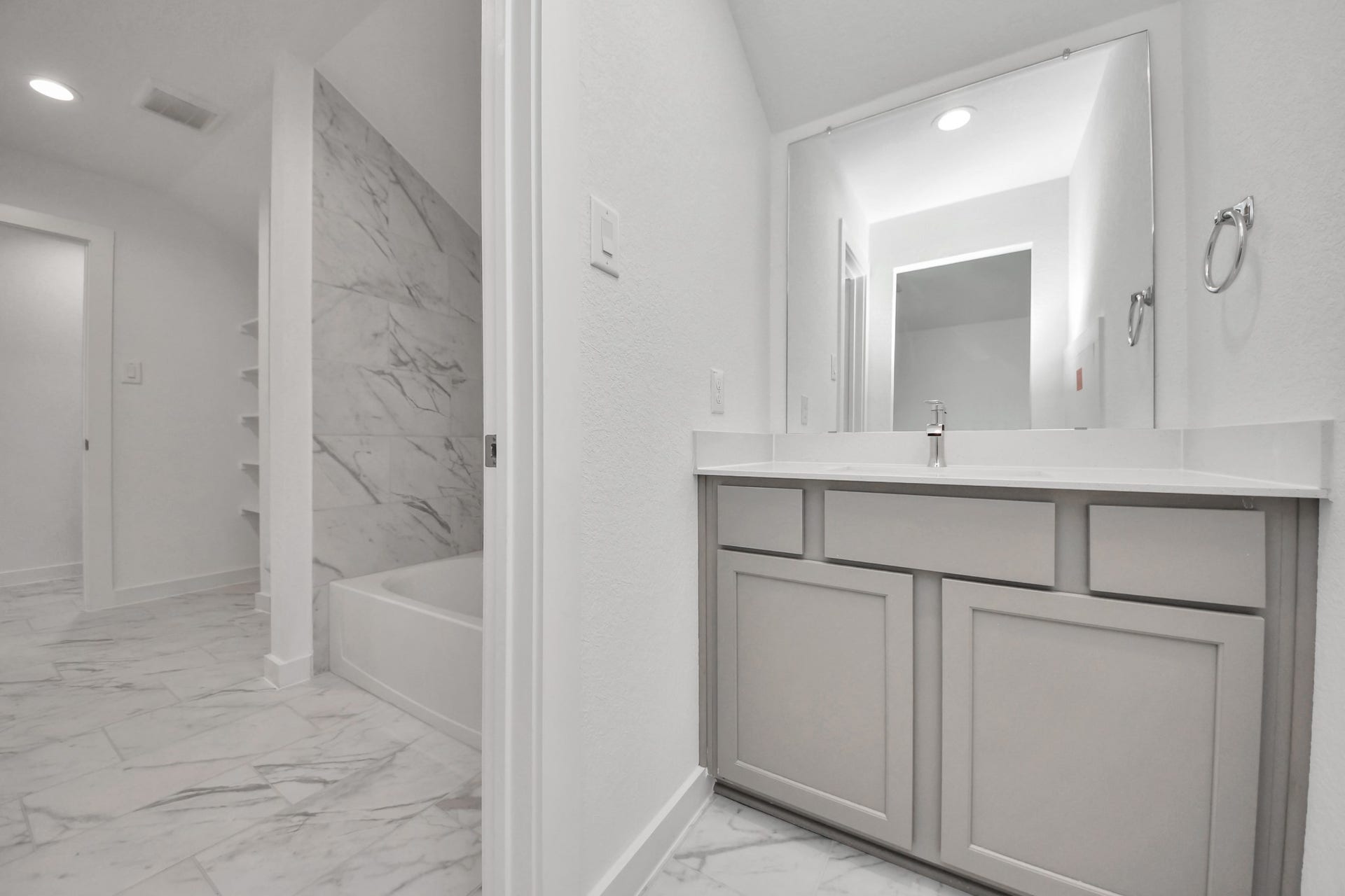 1017 Golden Glow Path, Magnolia, TX 77355 Experience convenience in the secondary bathroom, designed for Jack and Jill arrangements, now with a separate vanity area. This well-appointed space showcases stylish tile flooring, a bath/shower combo with an elegant tile surround, and light-stained wood cabinets. The beautiful light countertop adds a touch of sophistication, combining functionality and aesthetics seamlessly.