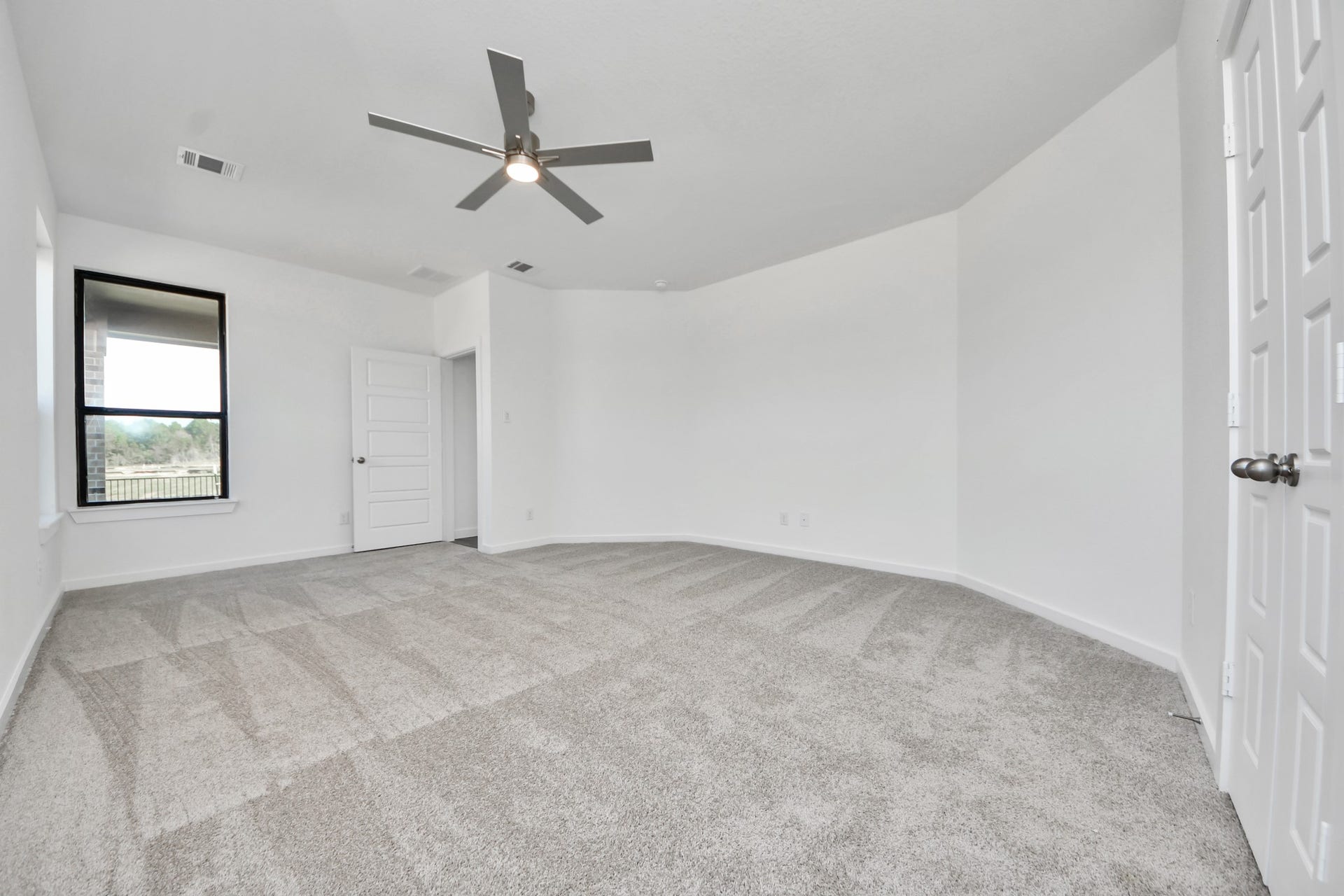 1017 Golden Glow Path, Magnolia, TX 77355 Retreat to the luxurious primary suite, your perfect escape for unwinding after a long day. Located on the first floor, this spacious room features plush carpeting, calming paint tones, high ceilings, and large windows with privacy blinds.