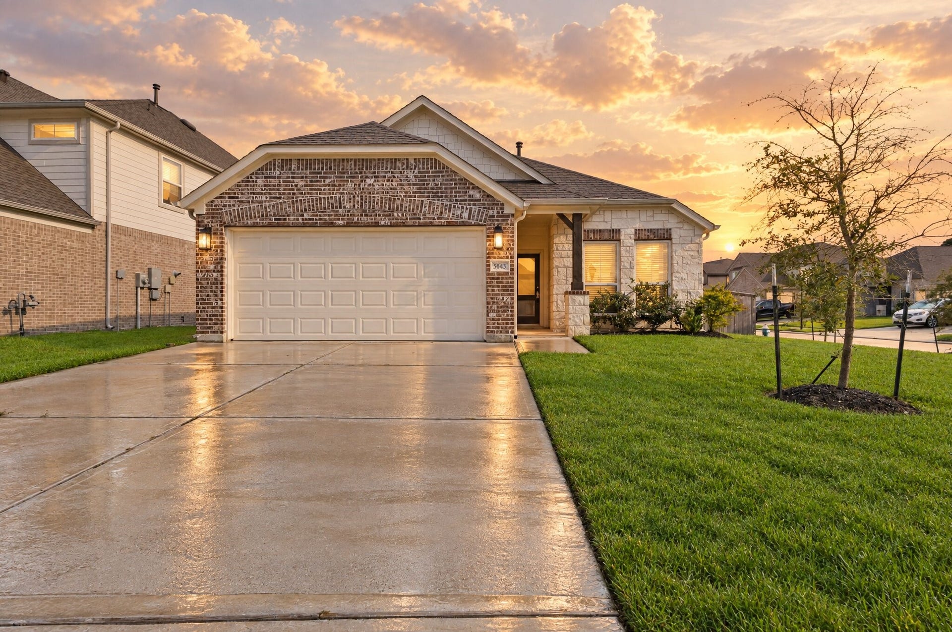 Golden hour sunset casts a warm glow over this home's brick and stone exterior, highlighting the charming gable roofline and covered entry with its stone accented column. This is the kind of curb appeal that makes you want to pull into the driveway and call it home. This photo has been virtually edited.