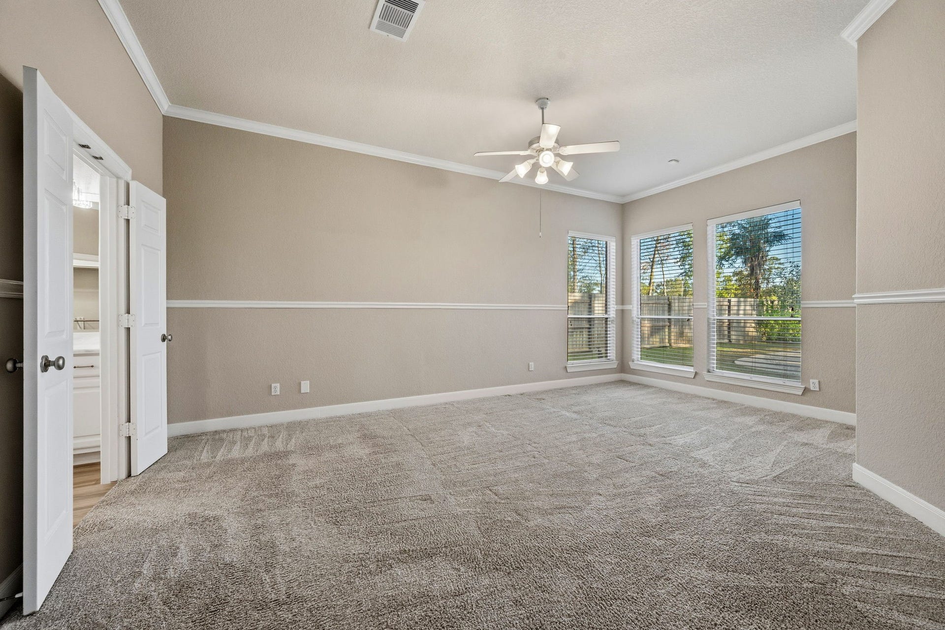 7514 Water Wood Trail, Kingwood, TX 77346 Spacious primary bedroom with neutral tones, featuring plush carpeting, crown molding, and large windows for abundant natural light.