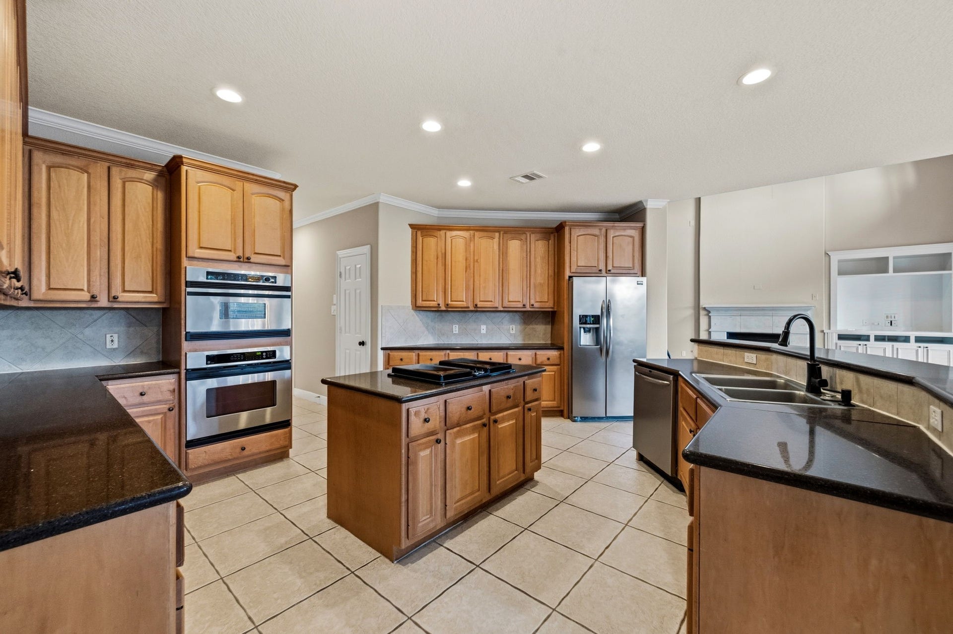 7514 Water Wood Trail, Kingwood, TX 77346 Spacious island kitchen with elegant wood cabinetry, granite countertops, and modern stainless steel appliances, featuring a convenient center island and ample storage.