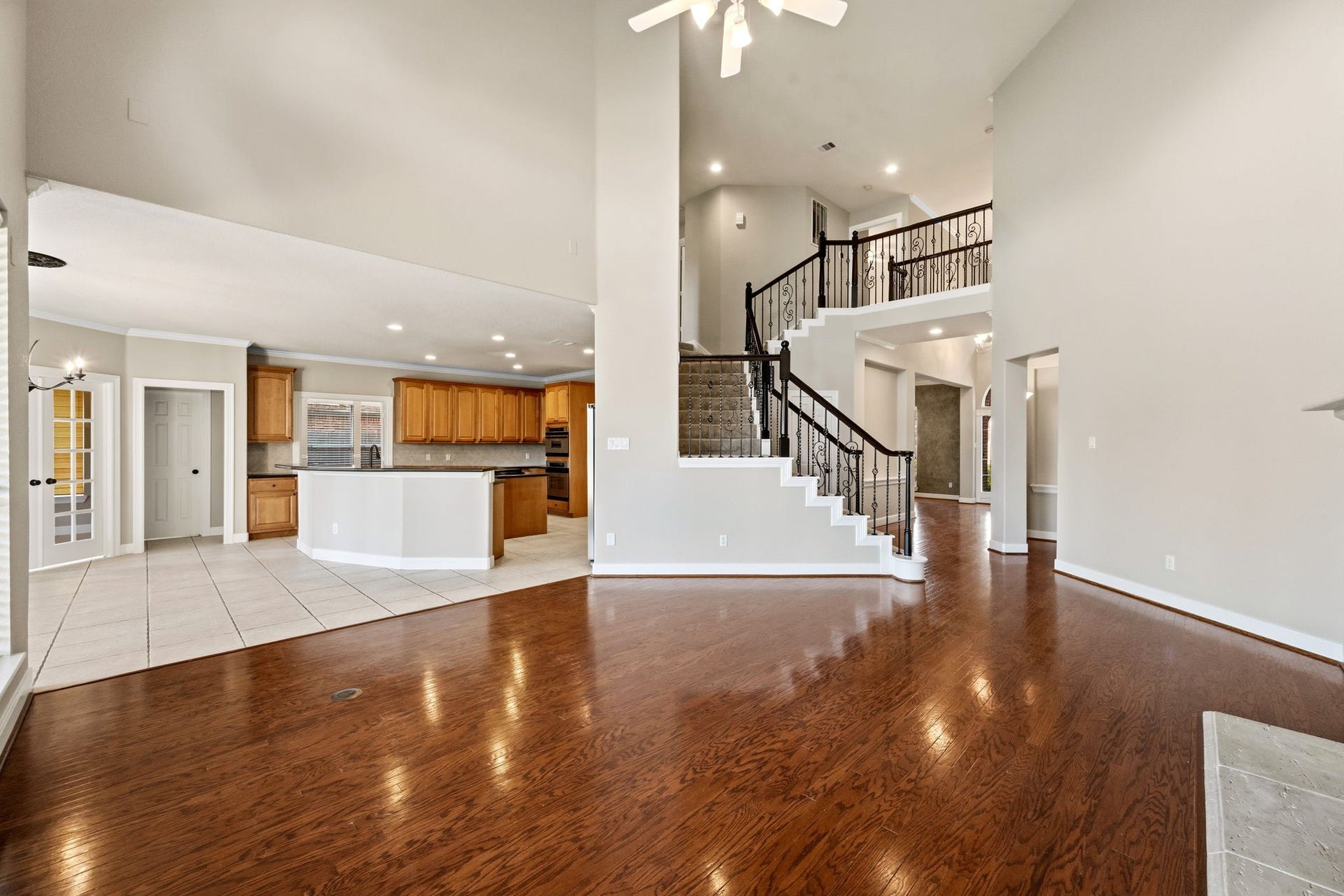 7514 Water Wood Trail, Kingwood, TX 77346 Spacious open-concept living area with elegant hardwood floors, a grand staircase, and a modern kitchen featuring ample cabinetry and a large island.
