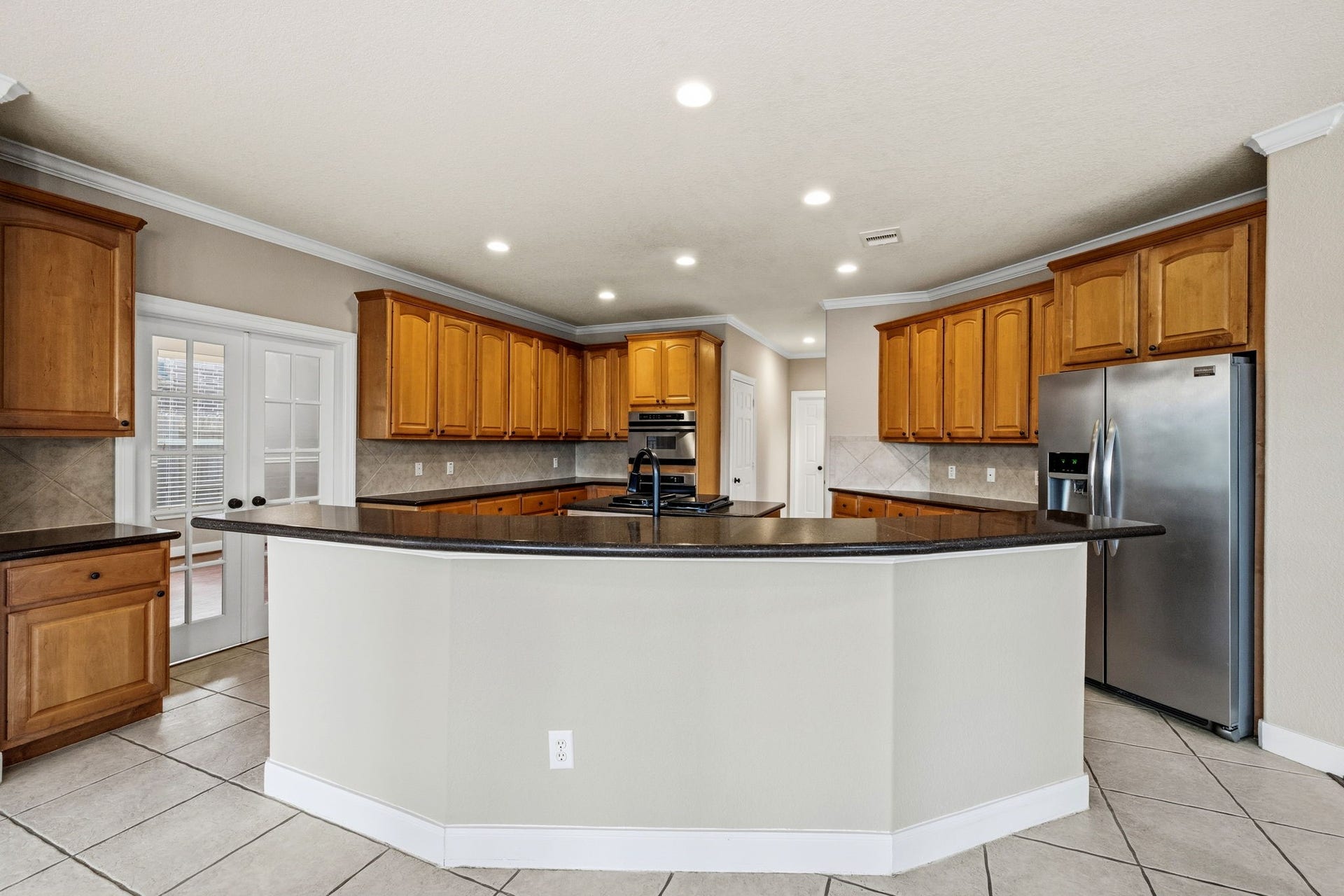 7514 Water Wood Trail, Kingwood, TX 77346 Spacious kitchen with a large curved island, granite countertops, stainless steel appliances, and ample wooden cabinetry.