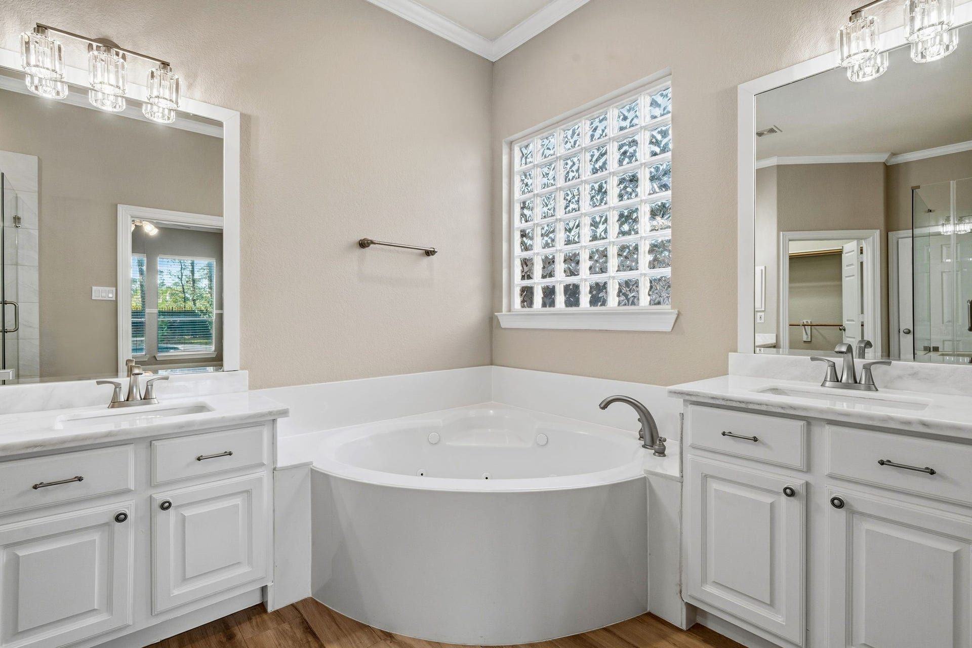 7514 Water Wood Trail, Kingwood, TX 77346 Elegant bathroom featuring a luxurious soaking tub, dual vanities with chic fixtures, and a large frosted window allowing natural light to flood the space.