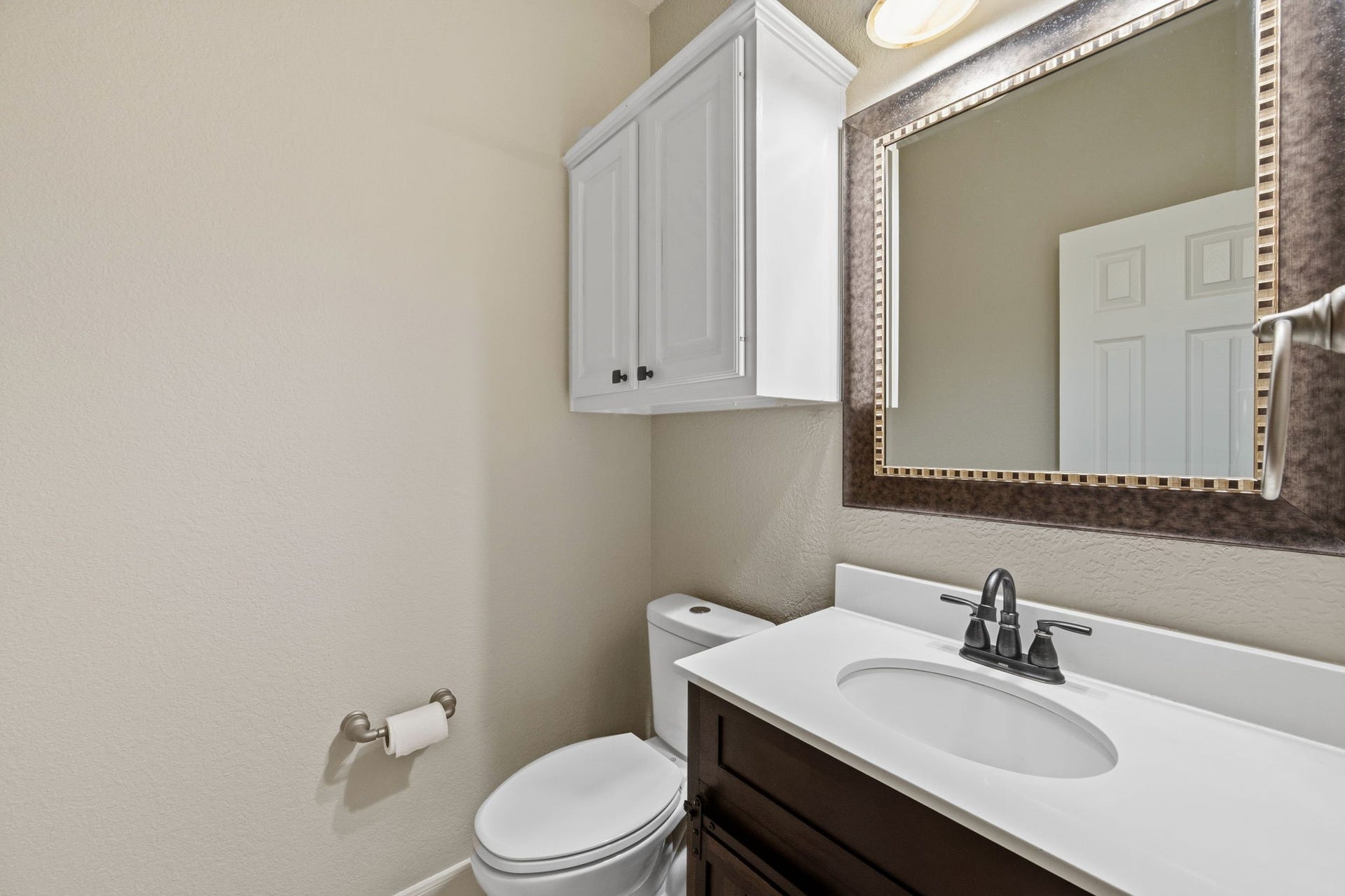 7514 Water Wood Trail, Kingwood, TX 77346 Charming powder room featuring a sleek vanity with a modern faucet, a stylish framed mirror, and convenient overhead cabinetry for extra storage.