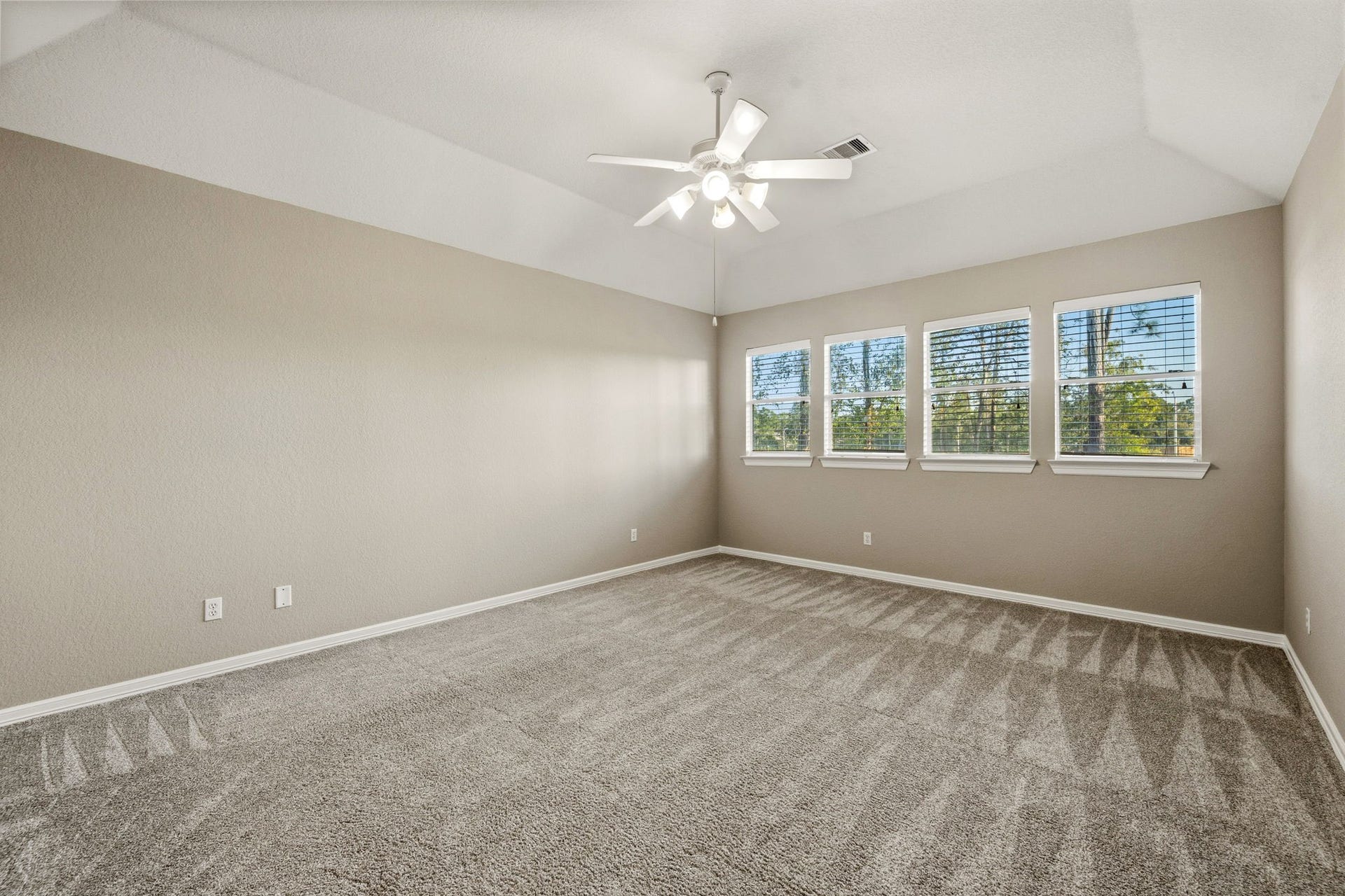 7514 Water Wood Trail, Kingwood, TX 77346 Spacious gameroom with plush carpet, large windows for natural light, and a modern ceiling fan, offering a cozy and inviting atmosphere.