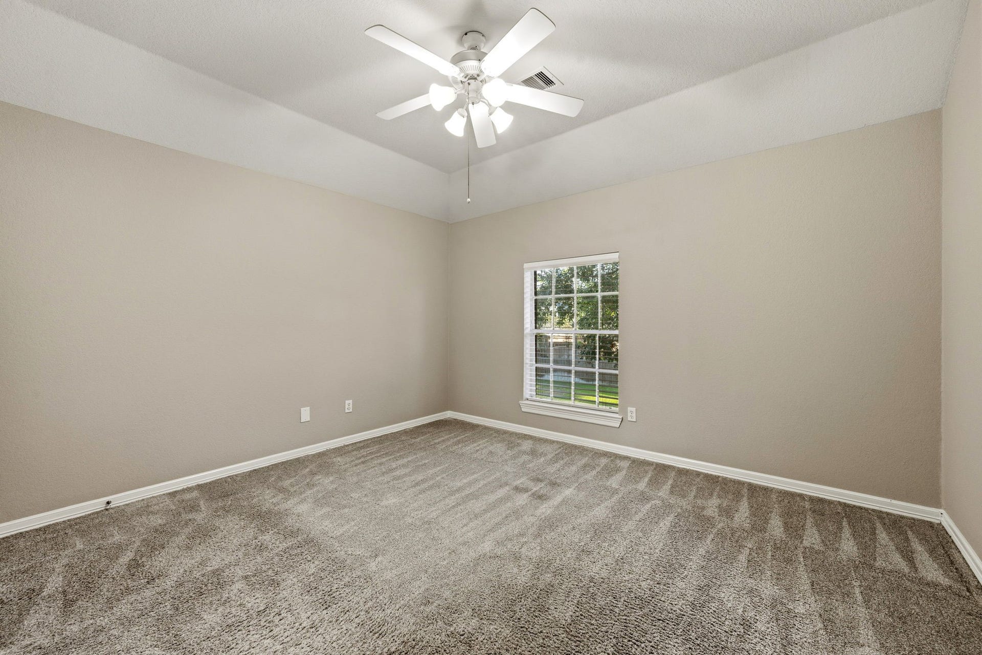 7514 Water Wood Trail, Kingwood, TX 77346 Spacious bedroom with plush carpeting and a large window for natural light, complemented by a ceiling fan for comfort.