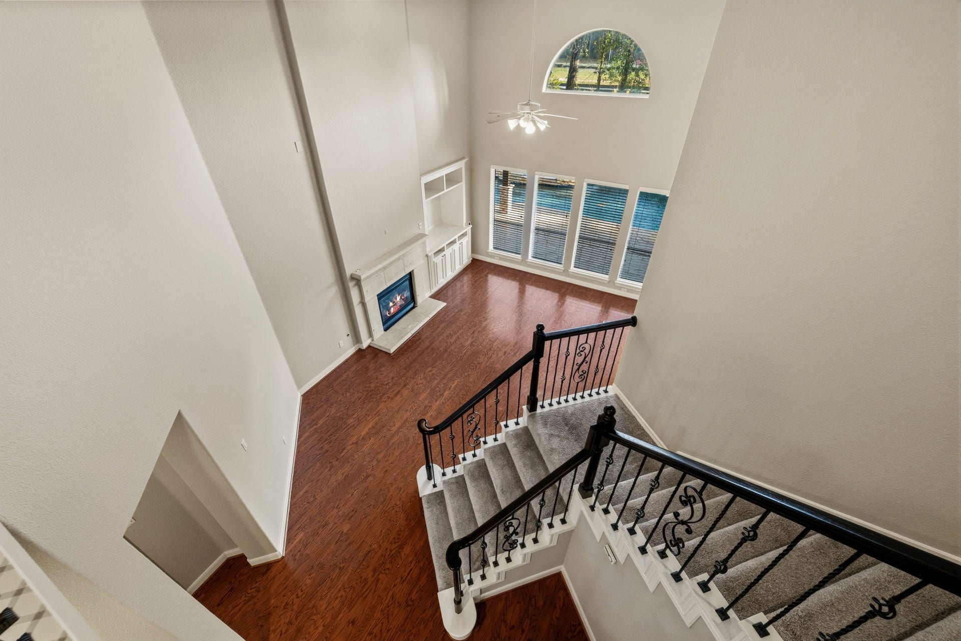 7514 Water Wood Trail, Kingwood, TX 77346 Stunning two-story living area with elegant staircase, rich wood floors, a cozy fireplace, and abundant natural light from expansive windows overlooking the backyard.