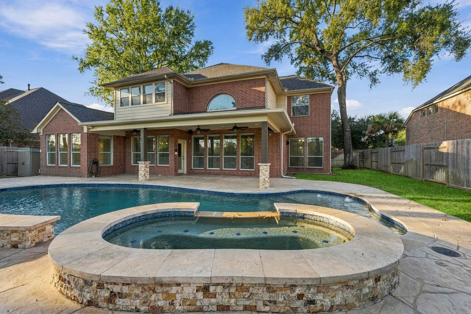 7514 Water Wood Trail, Kingwood, TX 77346 Stunning two-story brick home with a spacious backyard featuring a luxurious pool and spa, perfect for outdoor entertainment and relaxation.
