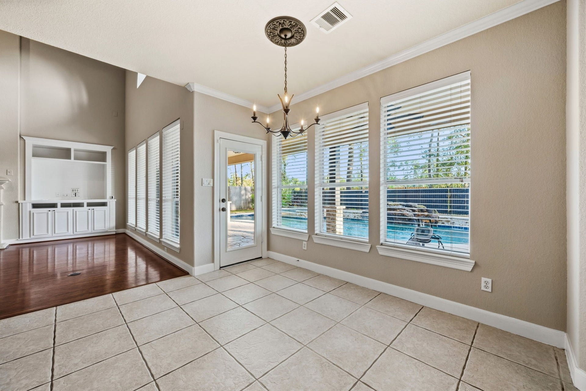 7514 Water Wood Trail, Kingwood, TX 77346 Bright dining area with tile flooring, adjacent to the living space and leading to backyard. Large windows and a glass door provide views of the inviting pool and patio.