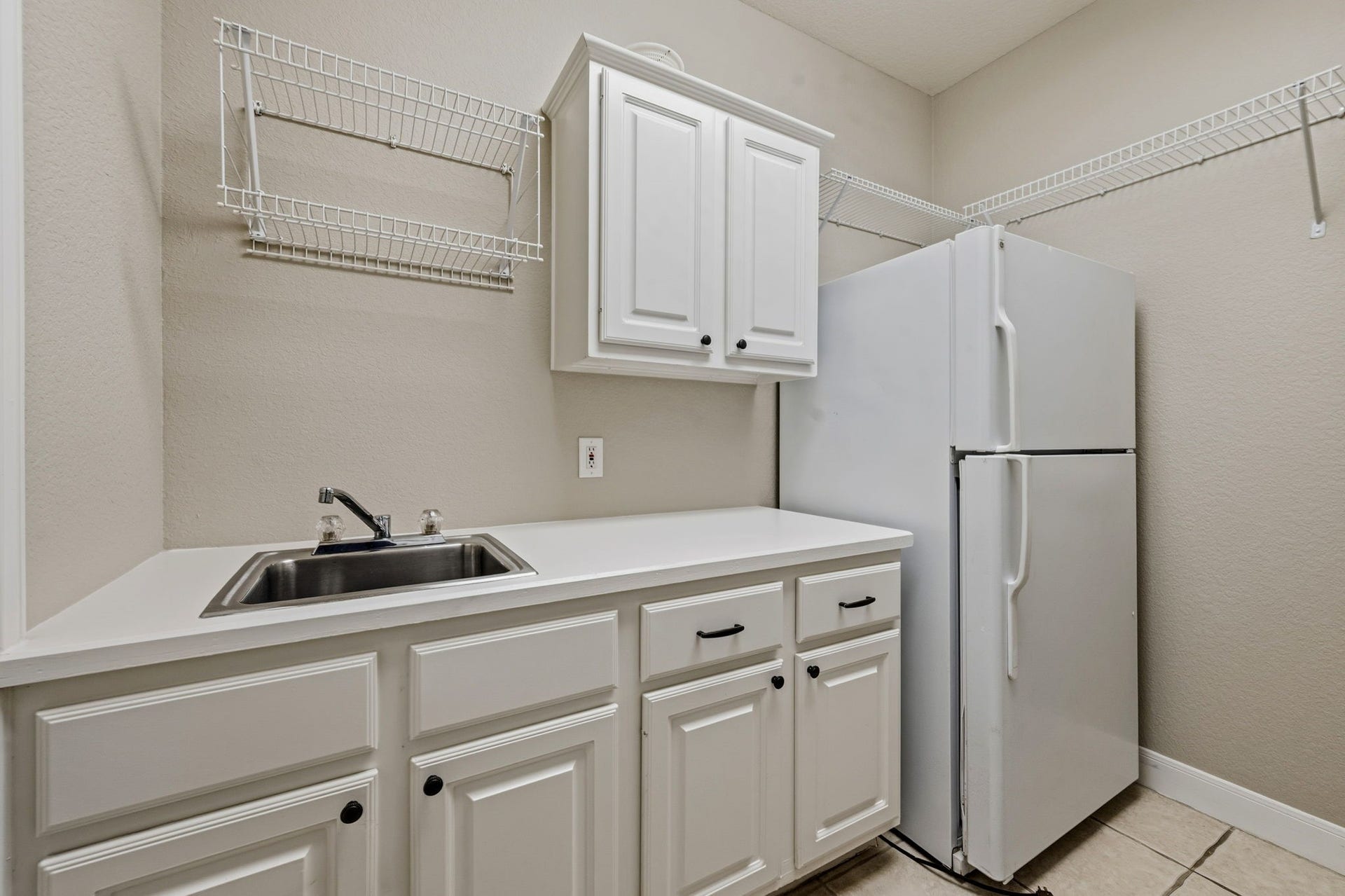 7514 Water Wood Trail, Kingwood, TX 77346 Spacious utility room featuring ample cabinetry, a sink, and a full-size refrigerator, complemented by convenient wire shelving for extra storage.