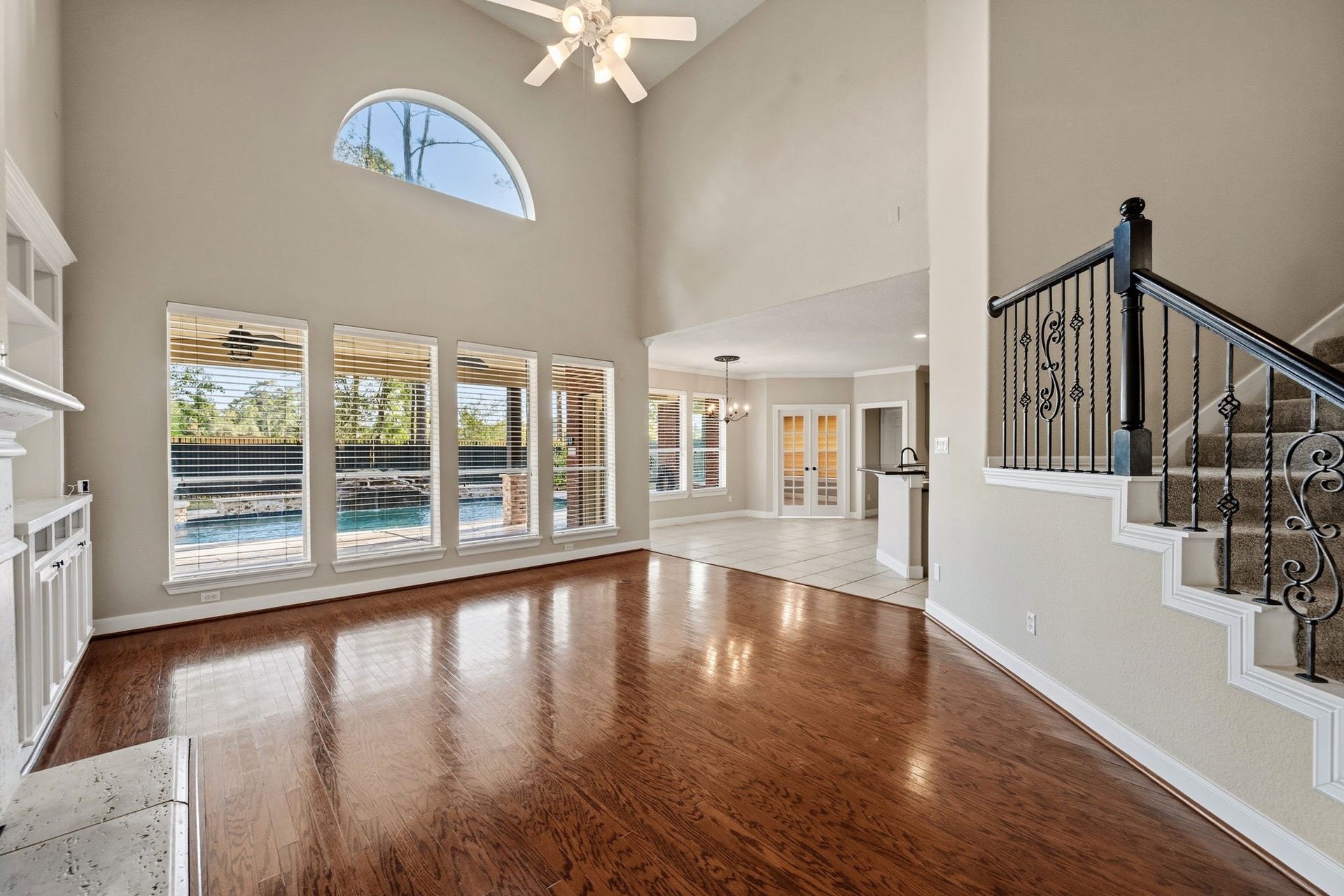 7514 Water Wood Trail, Kingwood, TX 77346 Spacious living area with high ceilings, elegant hardwood floors, and large windows offering a view of the pool. The open layout seamlessly connects to the kitchen and dining area, ideal for entertaining.
