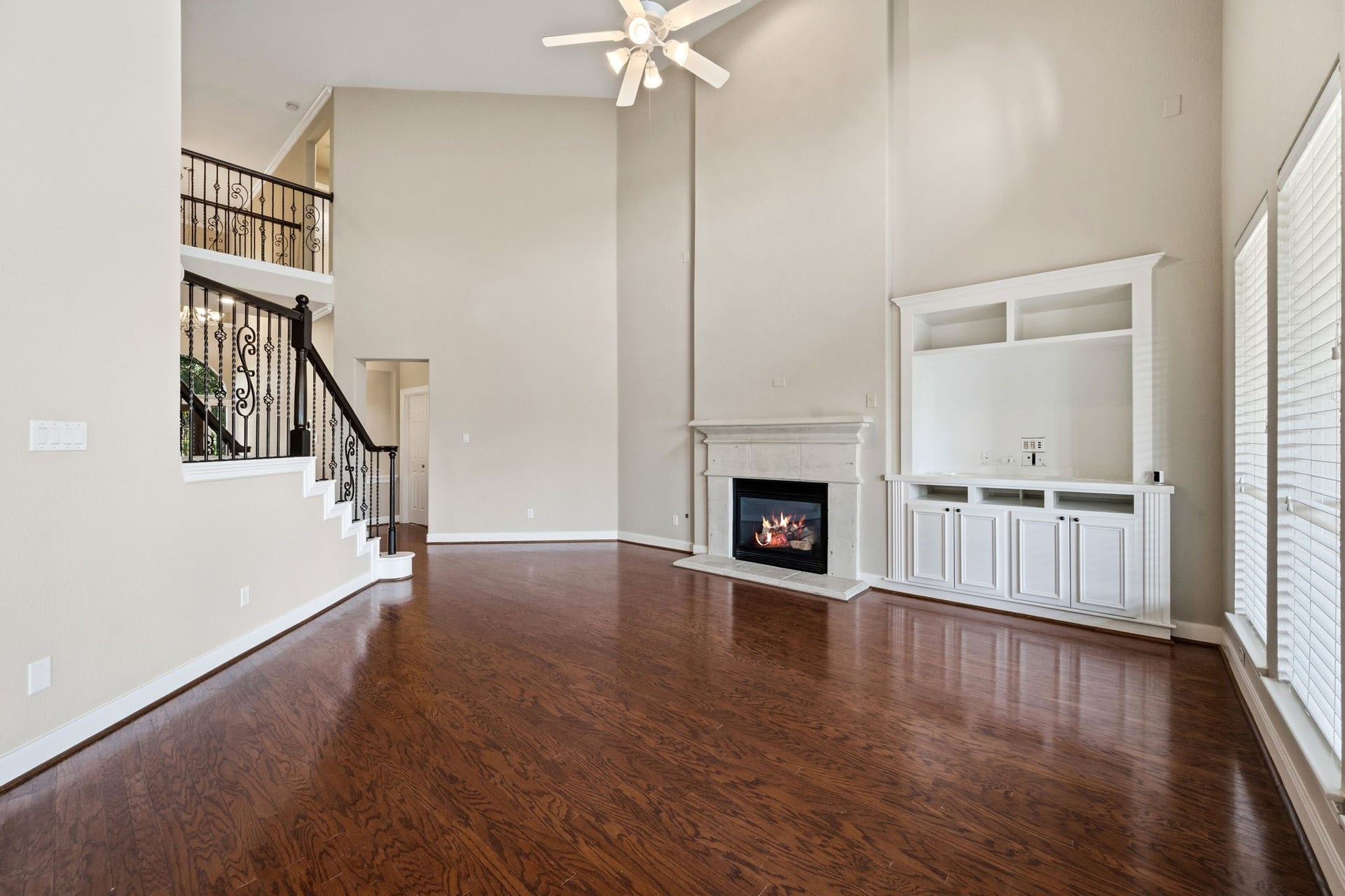 7514 Water Wood Trail, Kingwood, TX 77346 Spacious living room with soaring ceilings, elegant staircase, a cozy fireplace, built ins and abundant natural light from large windows.