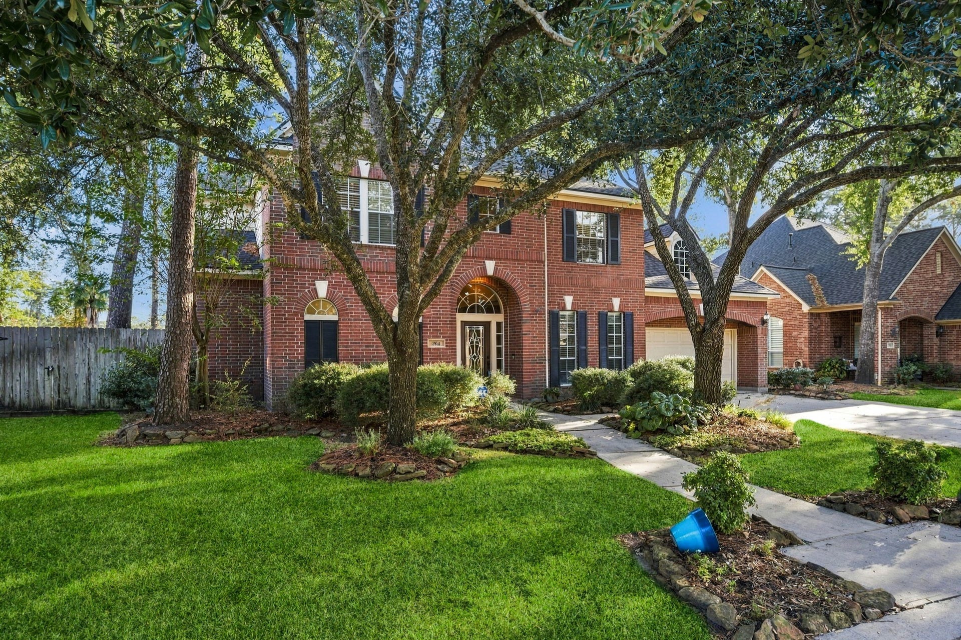 7514 Water Wood Trail, Kingwood, TX 77346 Charming two-story brick home with mature trees and lush landscaping, offering great curb appeal and a welcoming entrance.