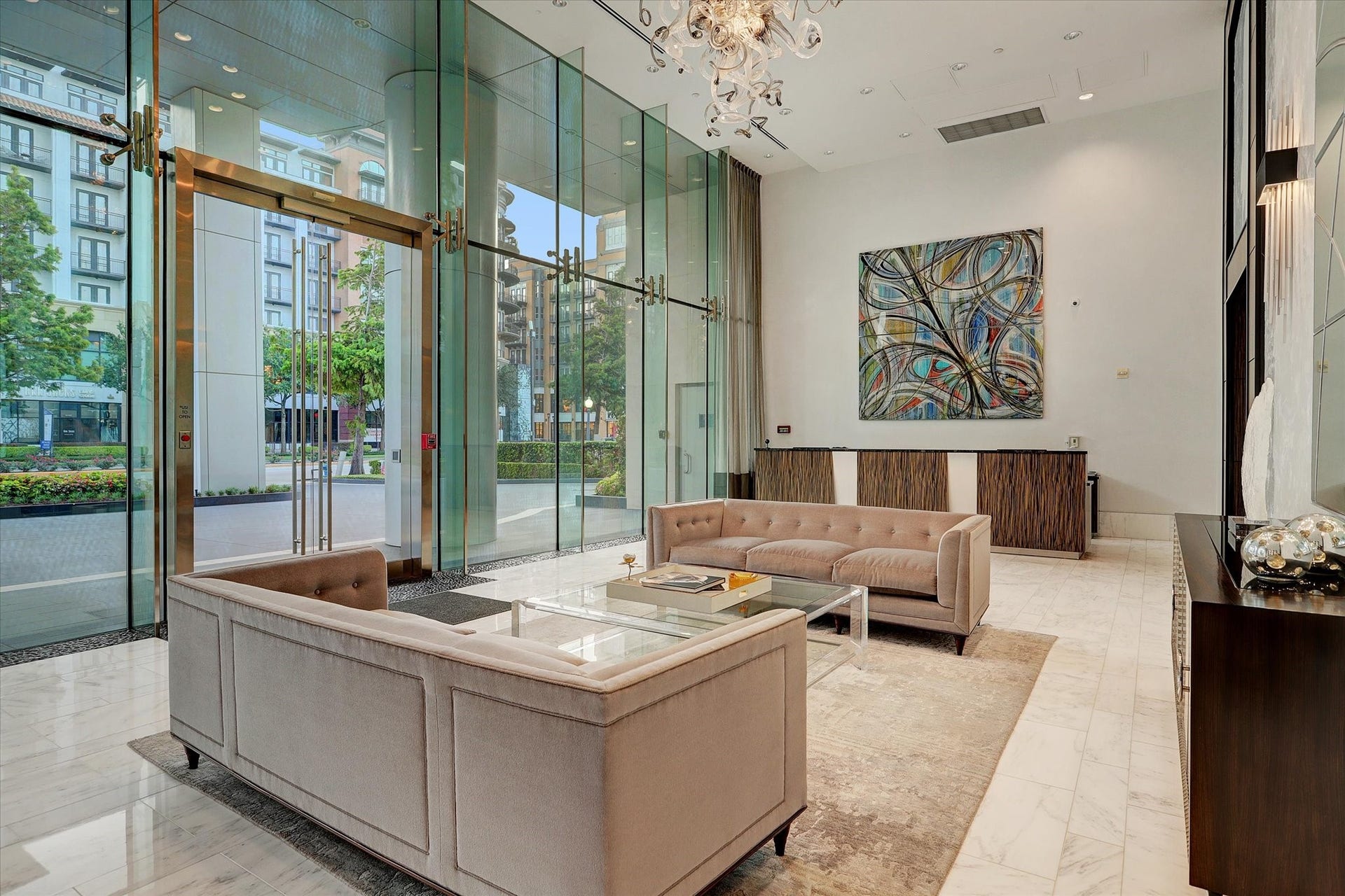 Elegant lobby with soaring glass walls, marble flooring, chandelier lighting, and secure concierge entry.