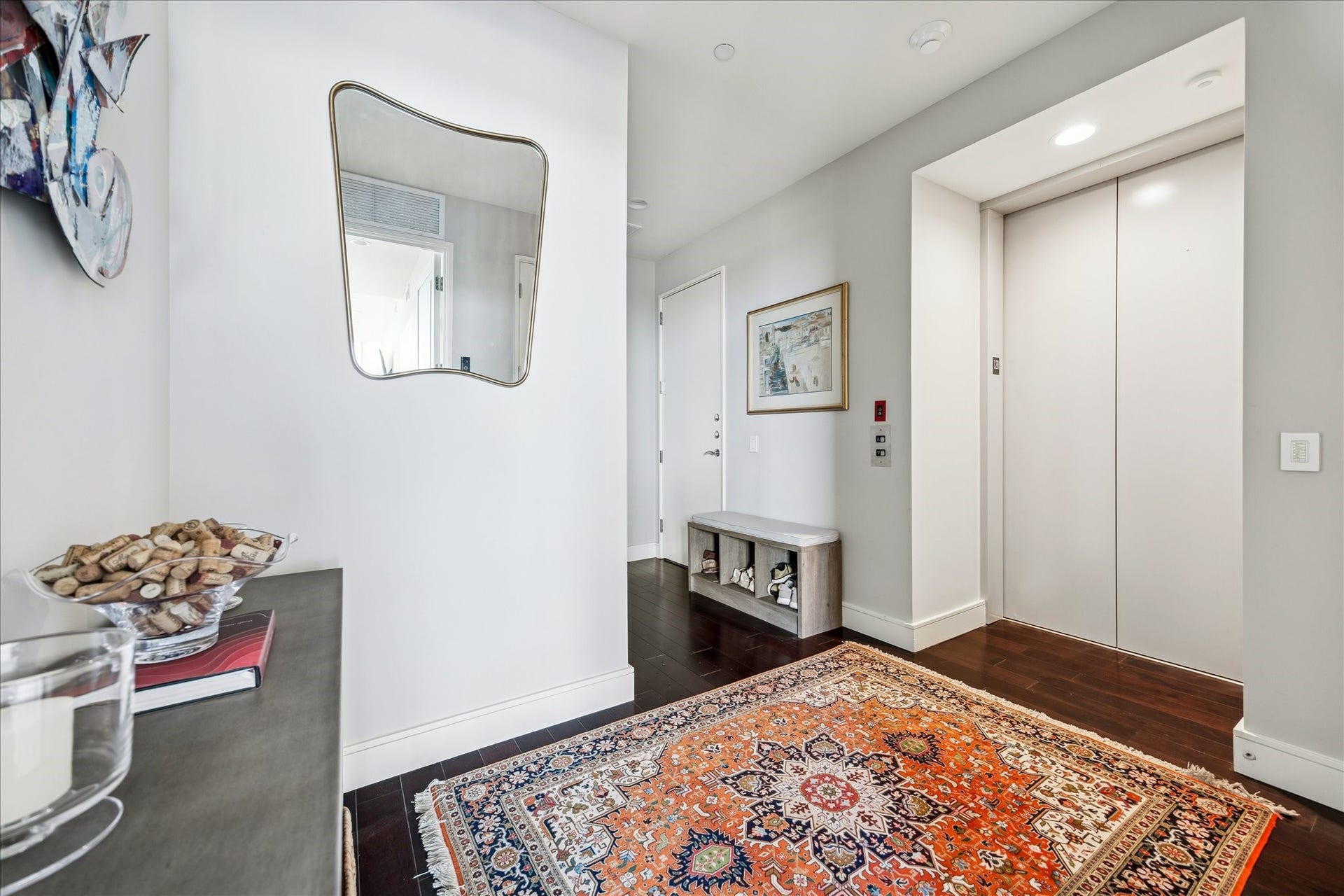 Direct elevator access opens to a foyer with hardwood floors, neutral wall tones, recessed lighting, and access to hallway and interior living spaces.