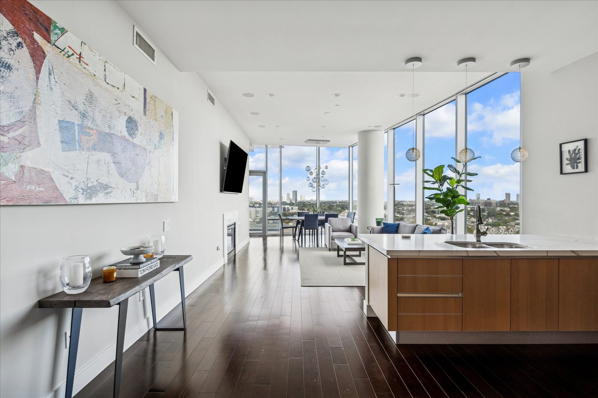View from kitchen toward living area featuring hardwood floors, quartz island, pendant lighting, and open-concept flow.
