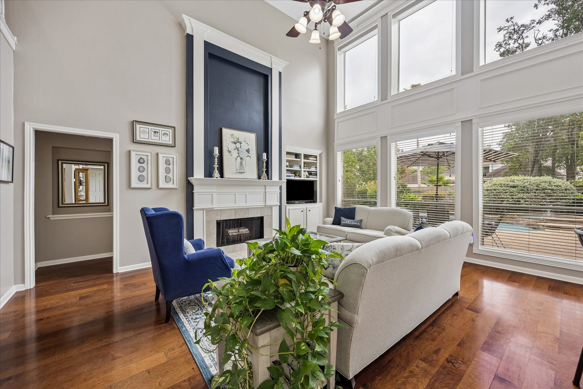 9618 Randon Lane, Missouri City, TX 77459 Two story Family Room with upgraded millwork surrounding and above the fireplace and the wall of windows. Rich wood flooring and on trend paint colors. This room offers a magnificent view of the lush landscaping and pool.
