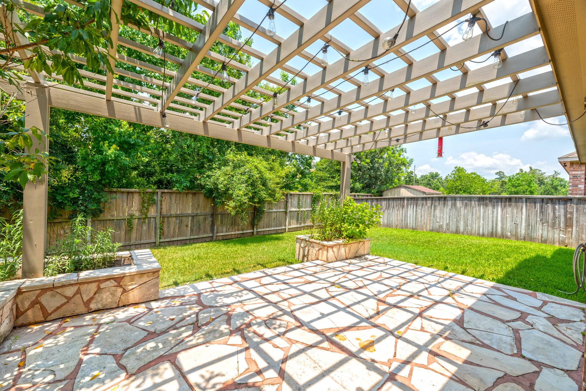 202 Black Swan Place, Magnolia, TX 77354 Large concrete patio with pergola and raised flower beds.