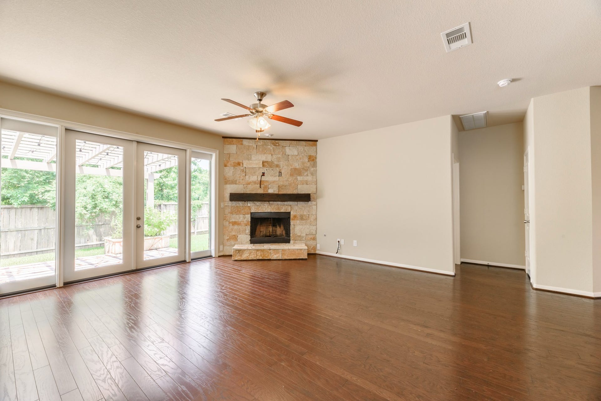 202 Black Swan Place, Magnolia, TX 77354 The living room has a gorgeous Austin Stone Fireplace, hardwood floors, custom installed French doors and large windows.
