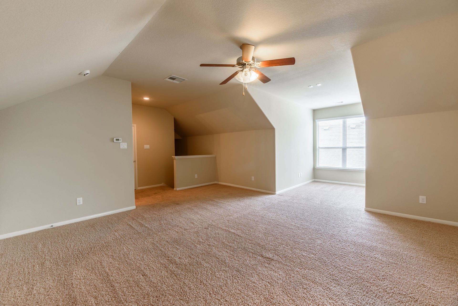 202 Black Swan Place, Magnolia, TX 77354 The upstairs game room has a large window, ceiling fan, and plush carpet.