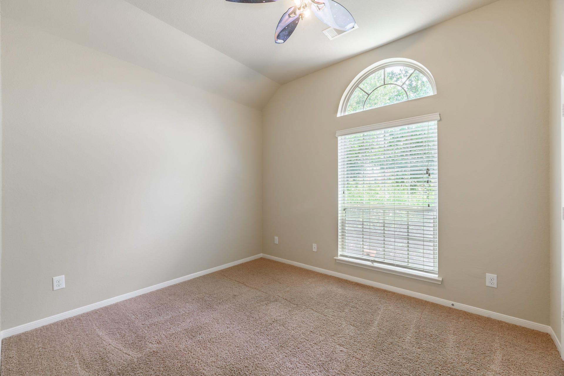 202 Black Swan Place, Magnolia, TX 77354 Secondary bedroom with large window, accent arched window, ceiling fan, and plush carpet.
