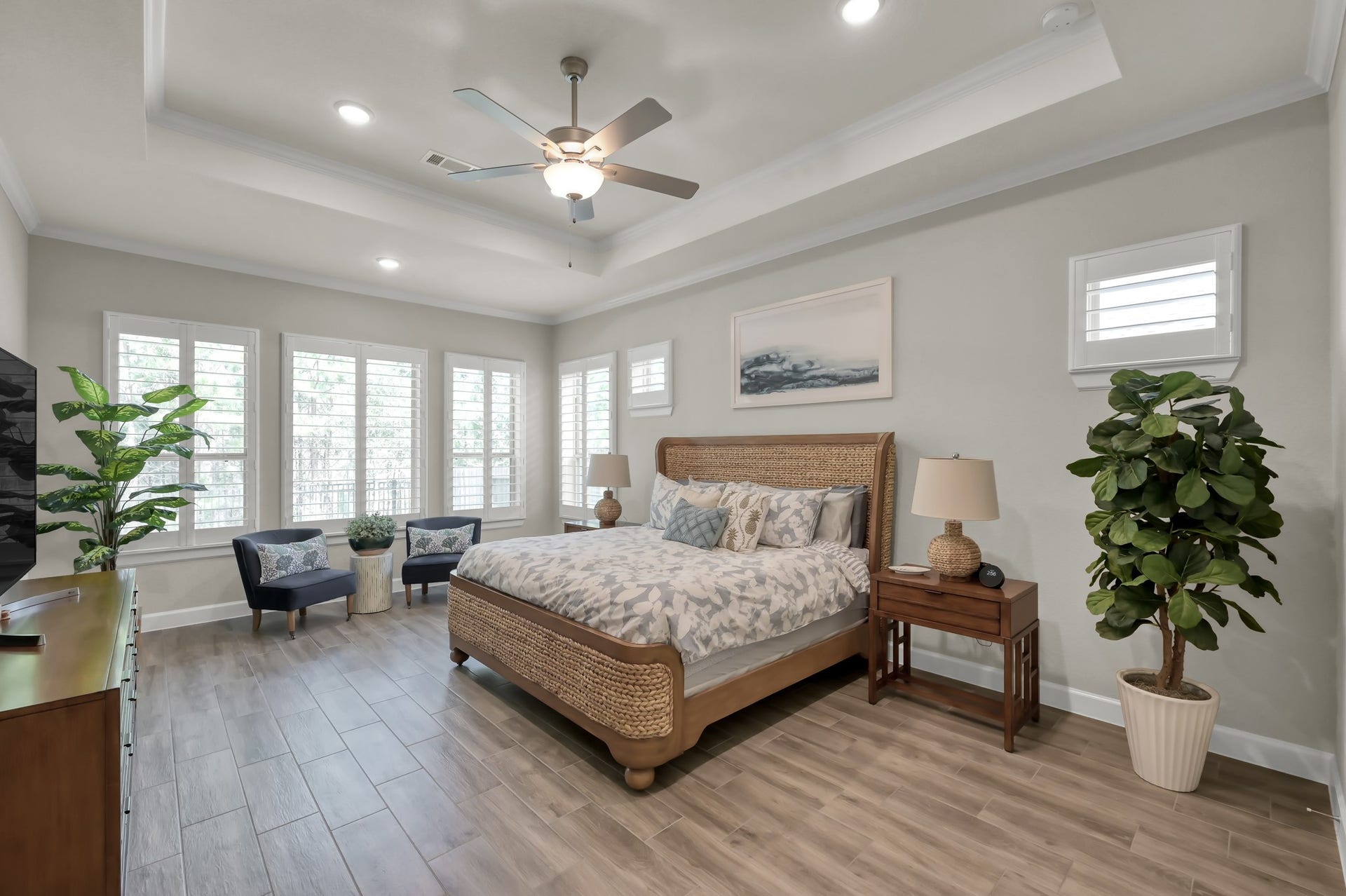 Spacious primary suite with tray ceiling, abundant natural light, and sitting areaoffering a peaceful retreat with serene backyard views.