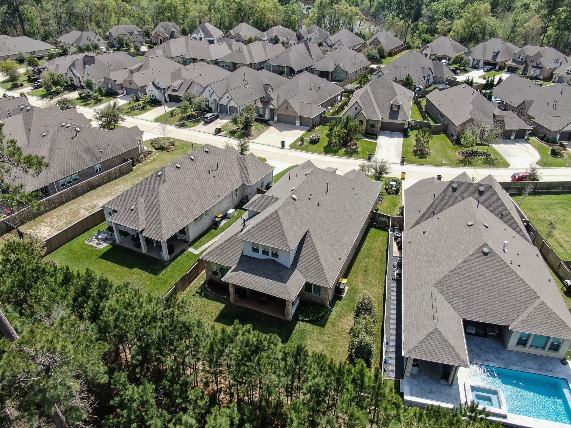 Aerial view showcasing a private backyard with no rear neighbors and a serene wooded backdrop in a well-maintained community.