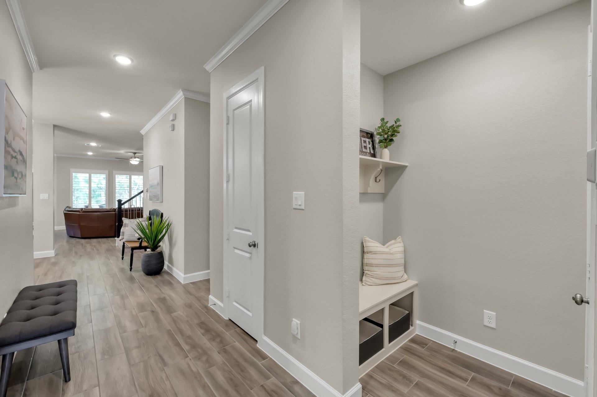 Functional mudroom/drop zone with built-in bench and storage, seamlessly connecting to the open-concept living area with continued wood-look flooring.