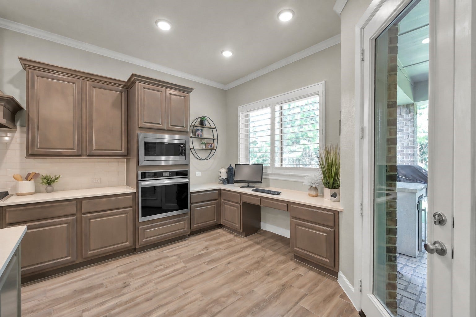 Virtually removed chair at desk. Thoughtfully designed kitchen workspace with built-in desk, ample cabinetry, and convenient access to the covered patioperfect for work or everyday organization.
