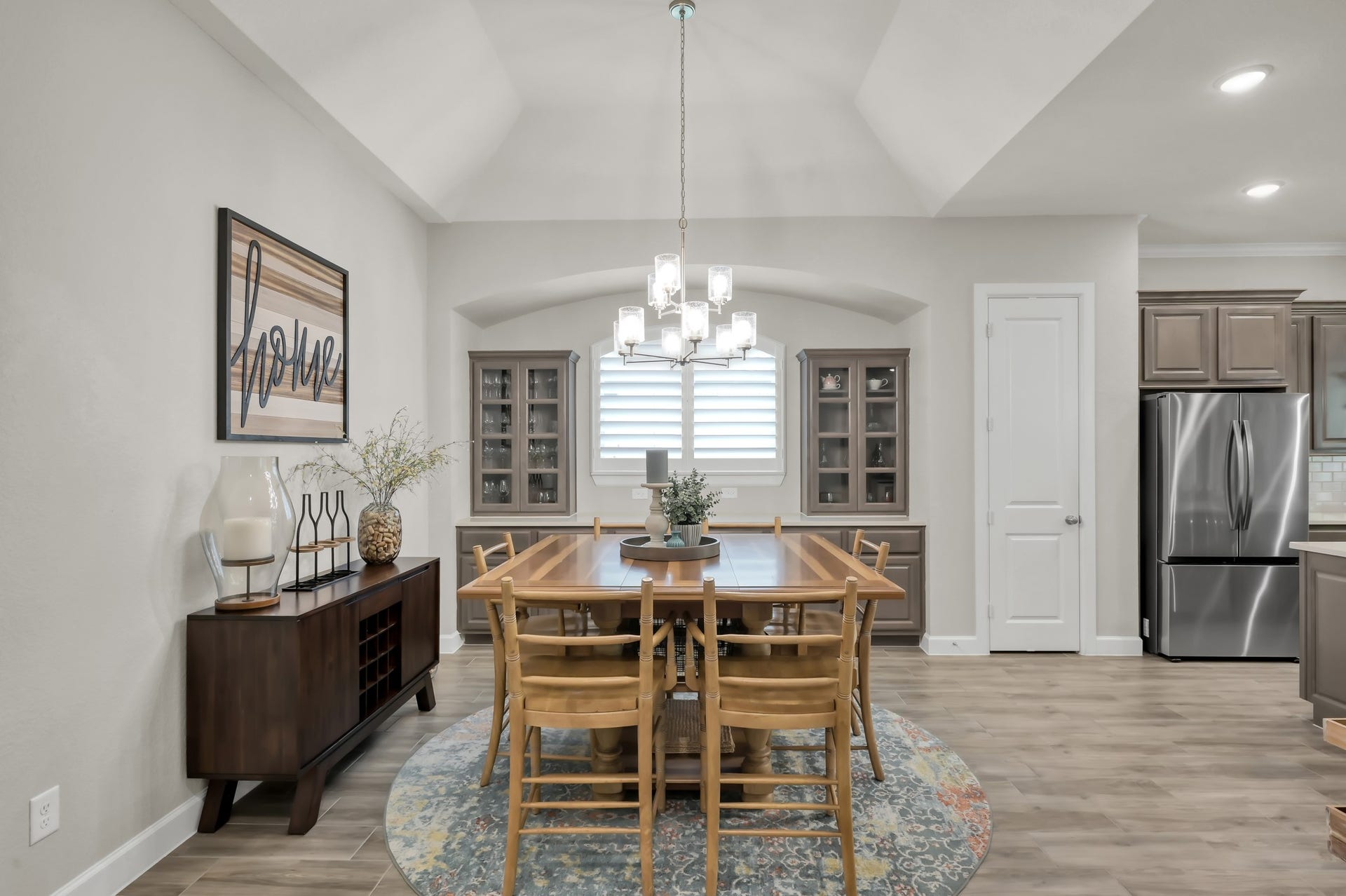 Elegant dining space with tray ceiling, statement chandelier, and custom built-ins, seamlessly connected to the kitchen for effortless entertaining.