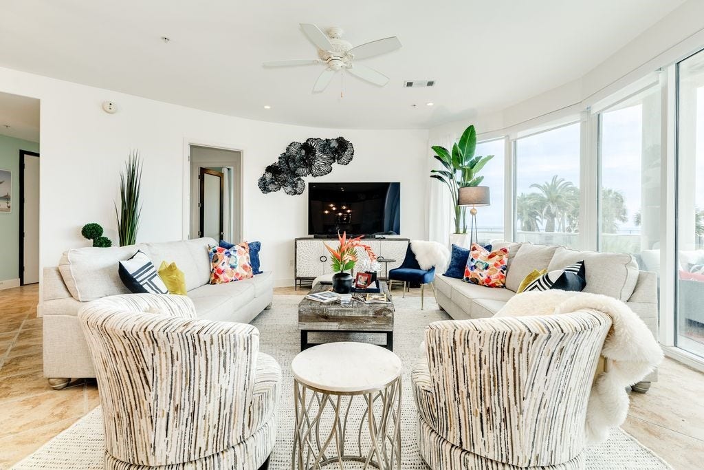 10327 Termini San Luis Pass Road, #218, Galveston, TX 77554 Beautifully appointed living room with a wall of curved windows overlooking the pools