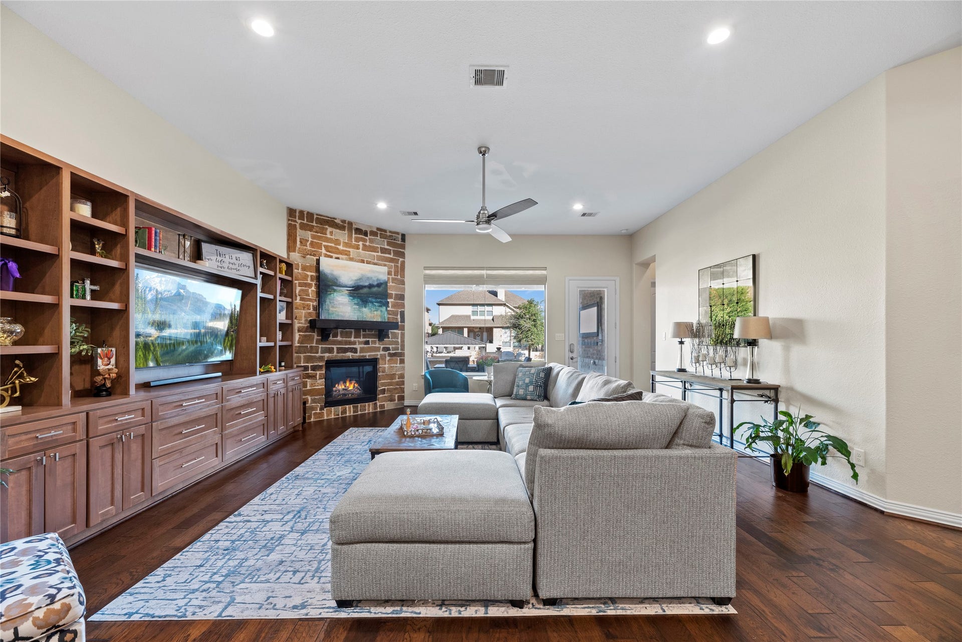 17922 Olde Oaks Estate Court, Cypress, TX 77433 Featuring a stone fireplace, electric shades, and a built-in entertainment center, this living room mixes elegance with functionality.