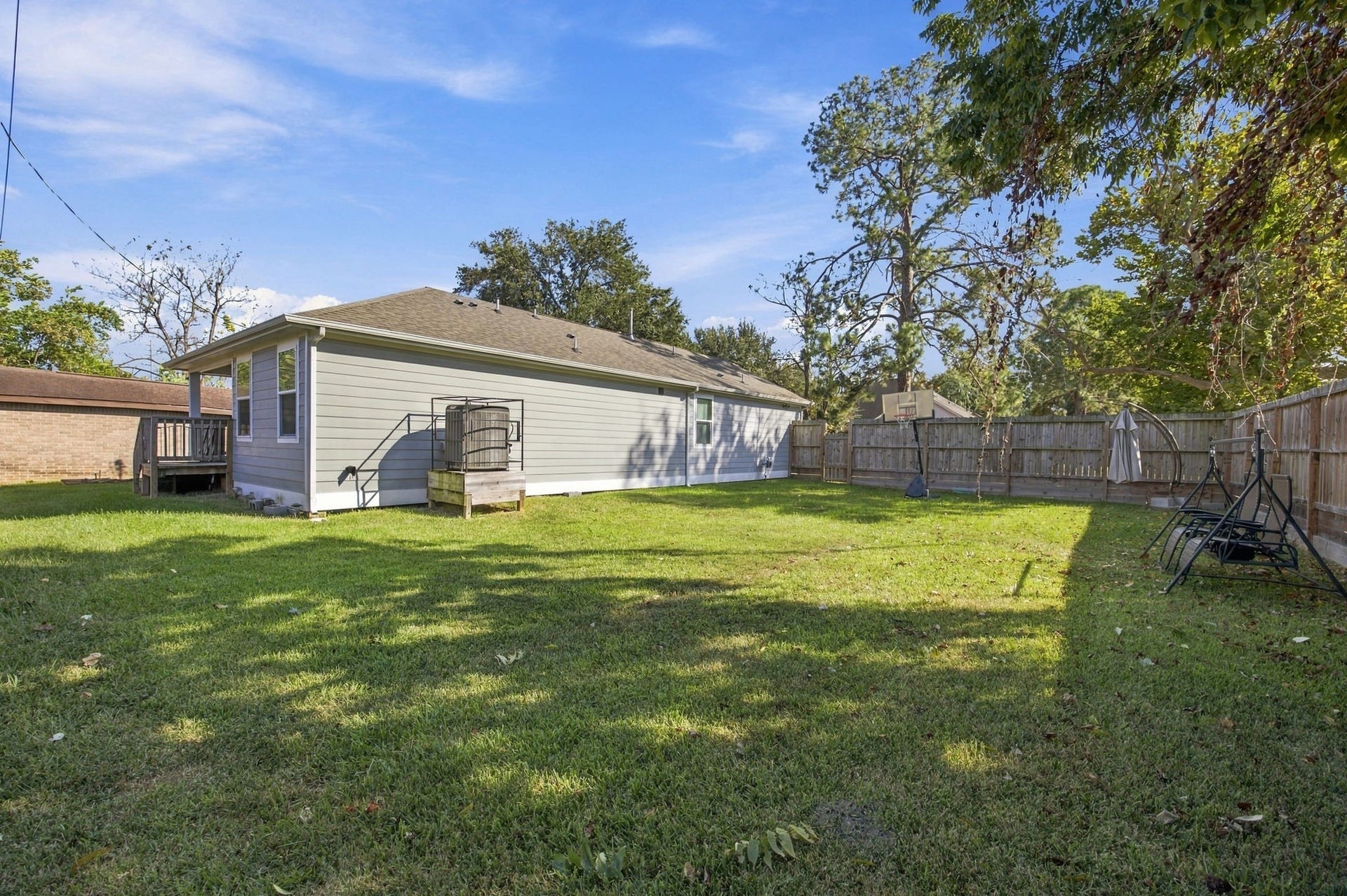 Spacious backyard featuring a well-maintained lawn, mature trees, and a wood privacy fence.