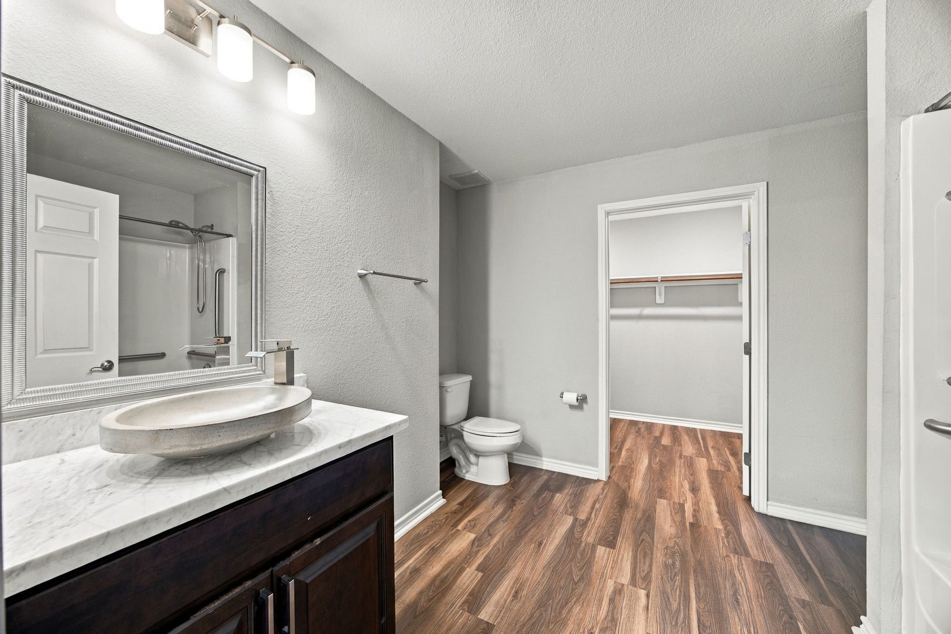 Bathroom featuring a modern vanity with marble-look countertop, vessel sink, large framed mirror, updated lighting, and walk-in closet access.