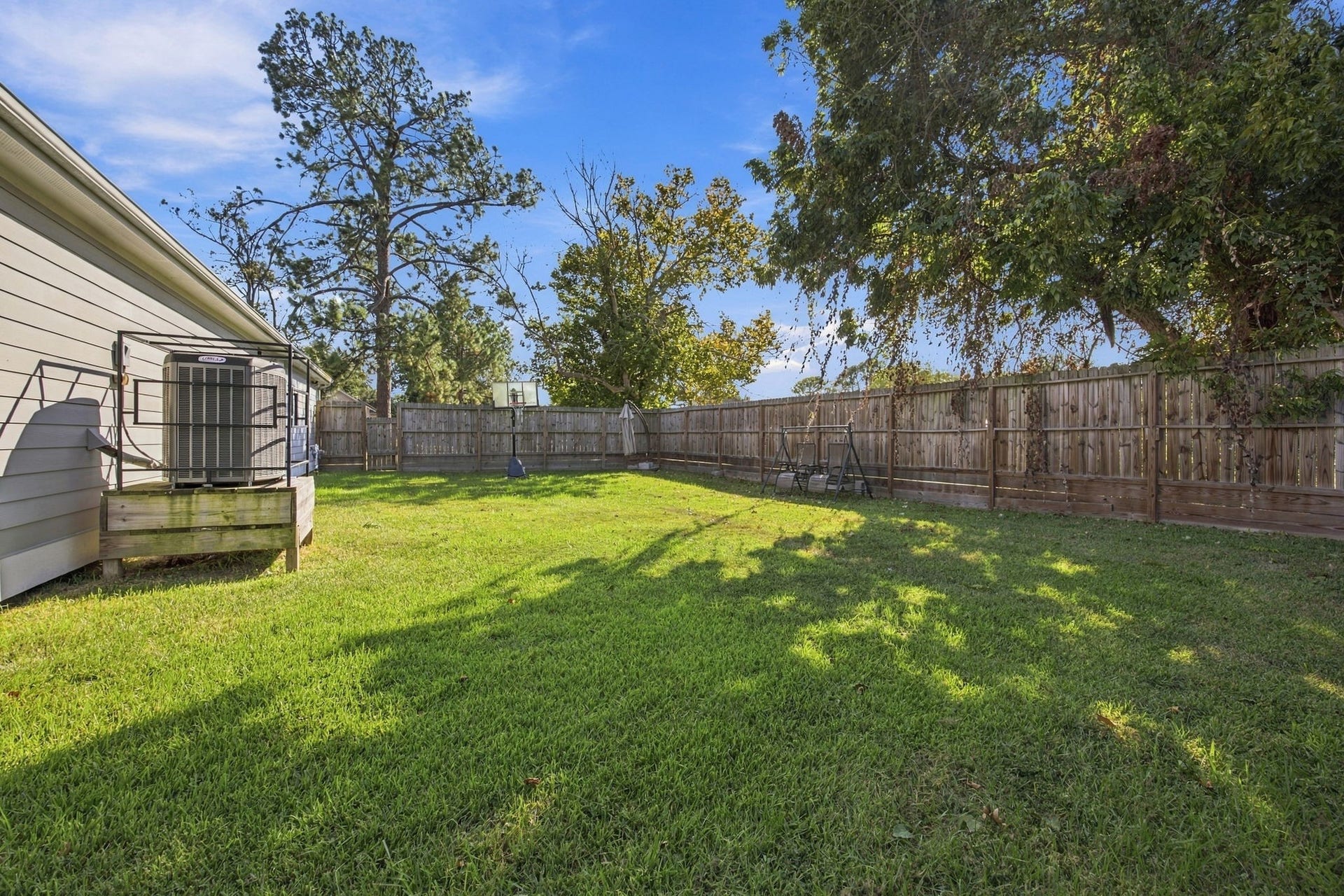Wide backyard view showcasing the expansive grassy area, fenced perimeter, and outdoor space.
