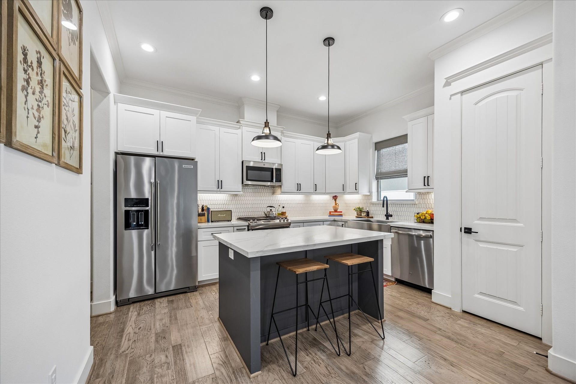 2320 Couch Street, Houston, TX 77008 This kitchen is ready for everything from quick breakfasts to lavish dinner parties. Quartz counters, crisp white cabinetry, designer tile backsplash with under cabinet lighting and a roomy island with bar seating and stylish pendant lights keep it polished, practical and easy to love.