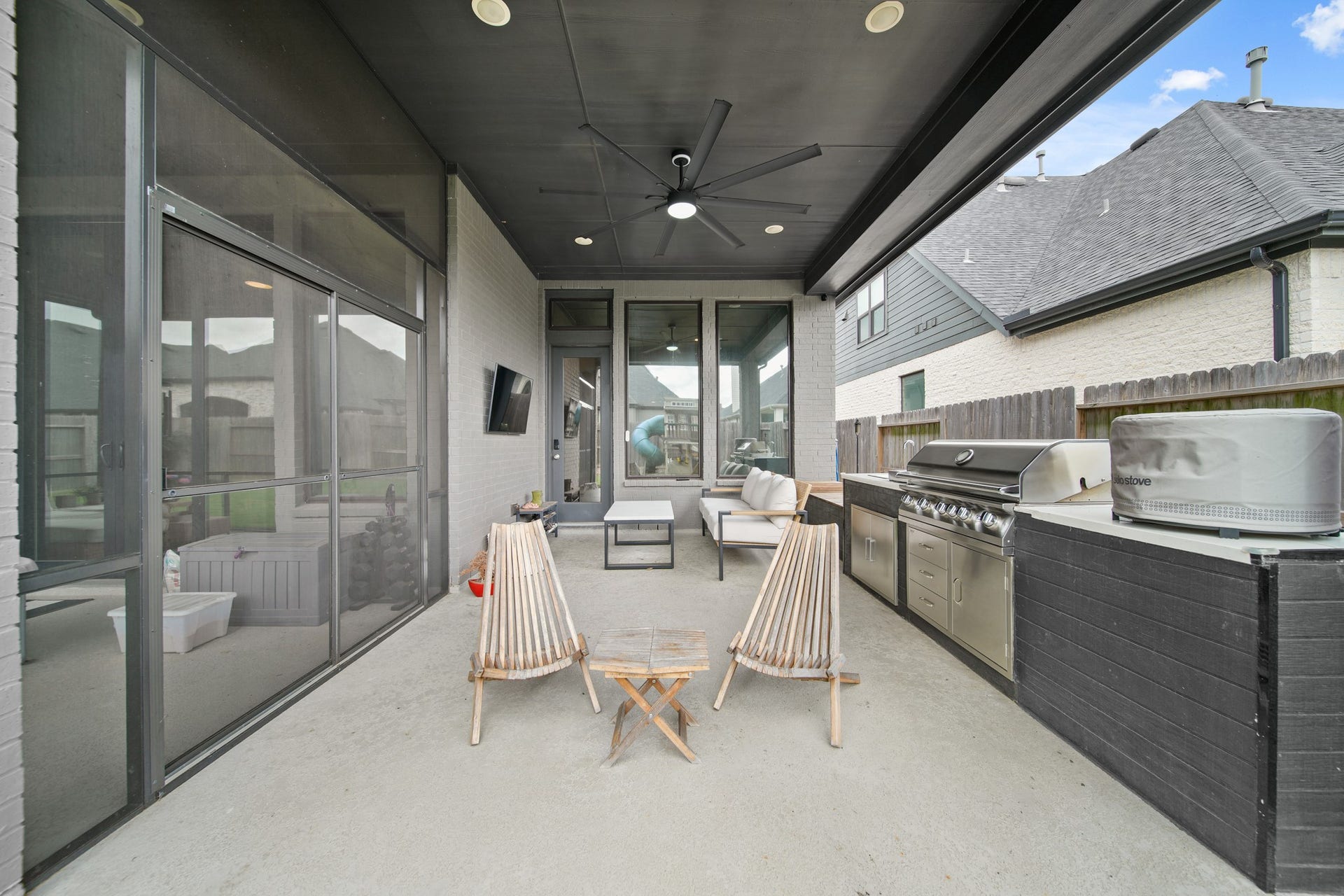 Outdoor gas kitchen with wall-mount television included.