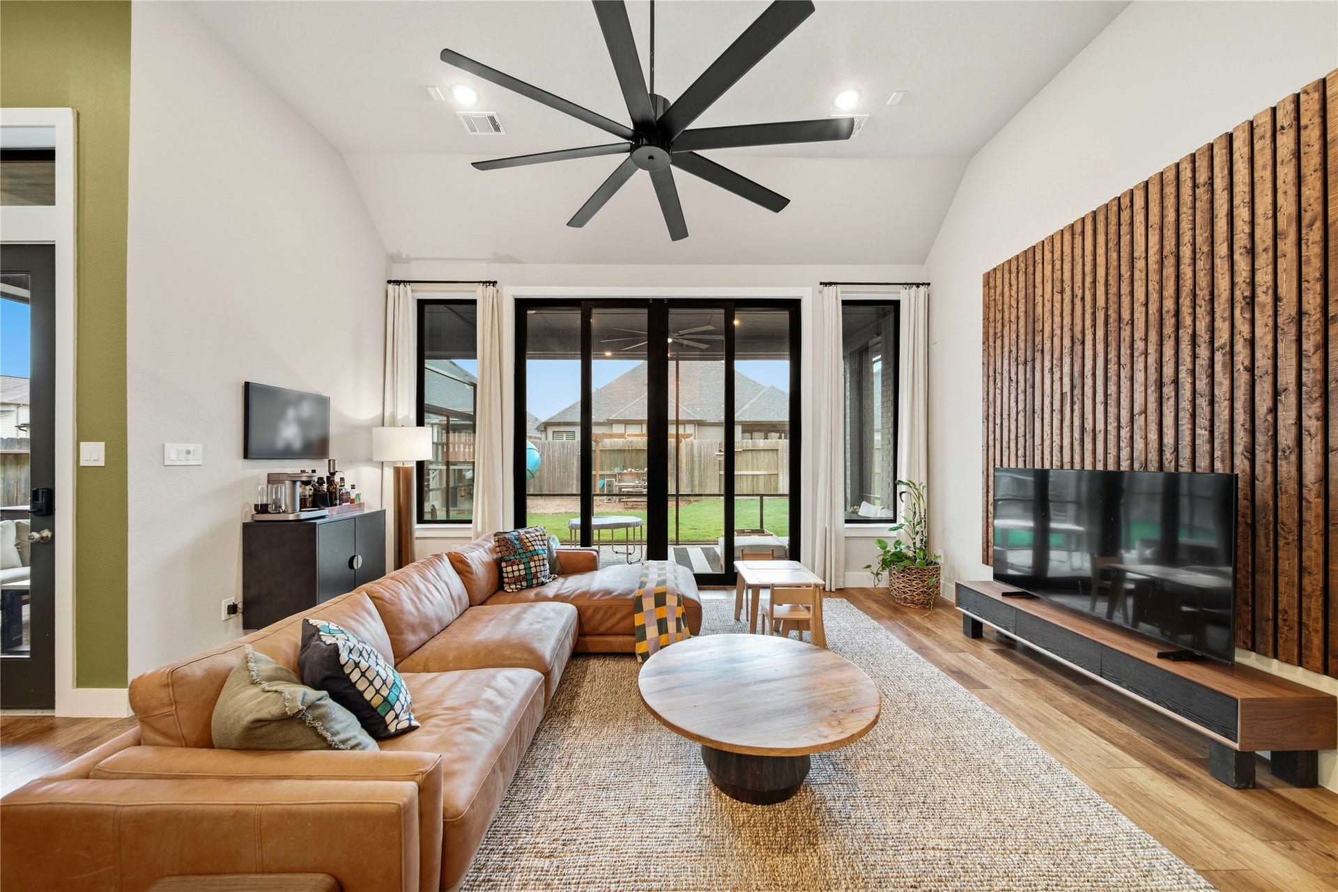 Family room with 13' ceilings. The 10' sliding doors open fully to the covered fully screened in patio. Enjoy indoor/outdoor entertainment.