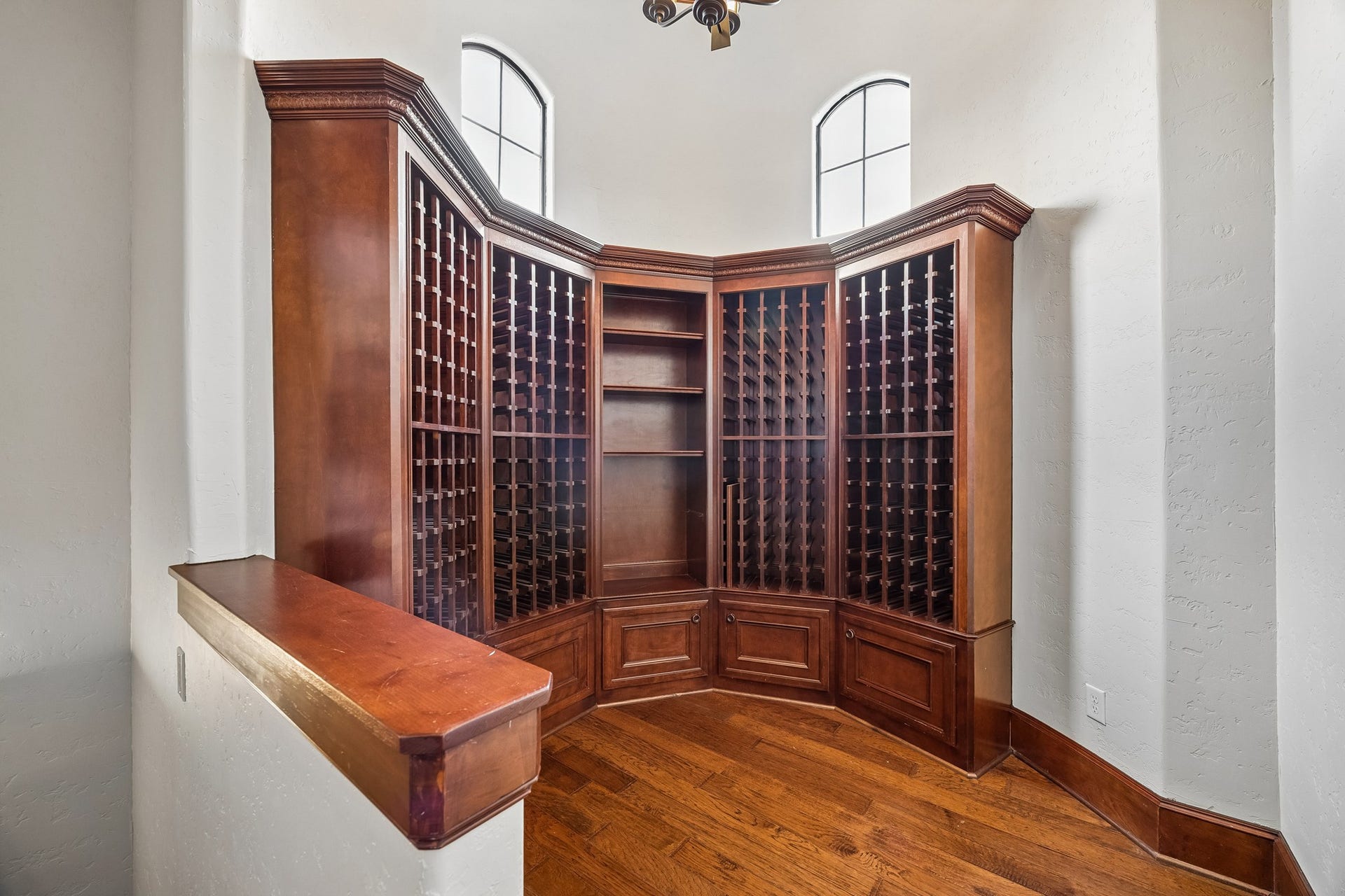 8111 Marshall Falls Drive, Spring, TX 77379 Elegant wine storage room featuring custom wooden cabinetry with ample shelving and natural light from arched windows, perfect for showcasing your collection. There is a back staircase that leads to the garage.