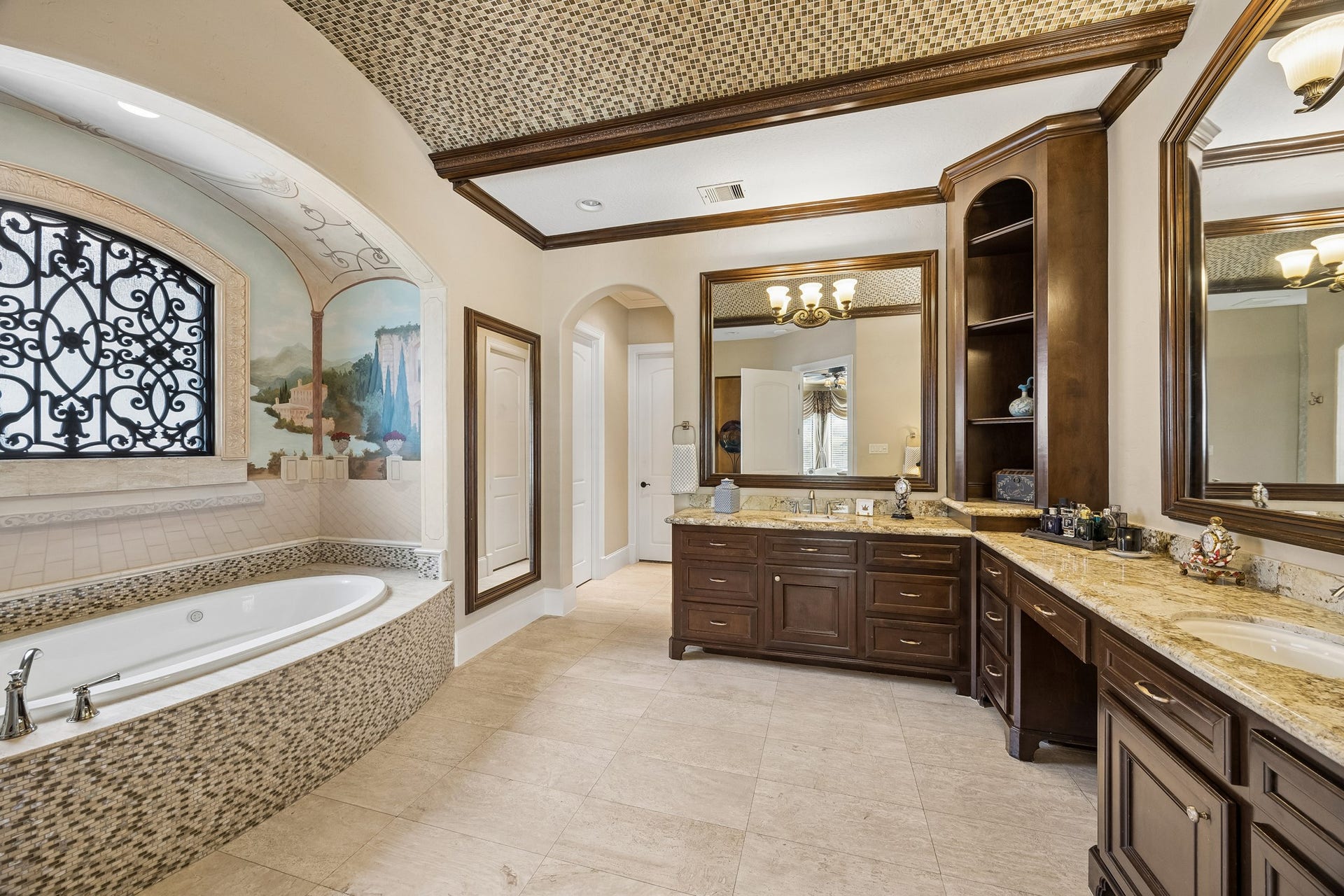 8111 Marshall Falls Drive, Spring, TX 77379 Luxurious bathroom featuring a spacious soaking tub with intricate tile work, elegant dual vanities with rich wood cabinetry, and a beautifully detailed barrel vaulted ceiling.