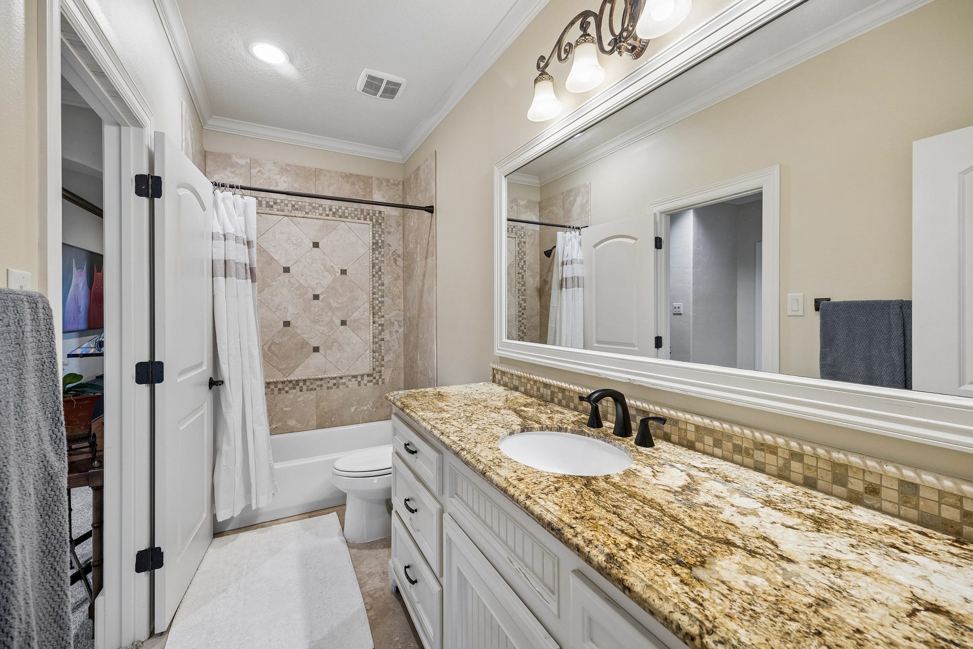 8111 Marshall Falls Drive, Spring, TX 77379 Elegant en-suite bathroom featuring a granite countertop, stylish fixtures, and a beautifully tiled shower area with a decorative inlay.