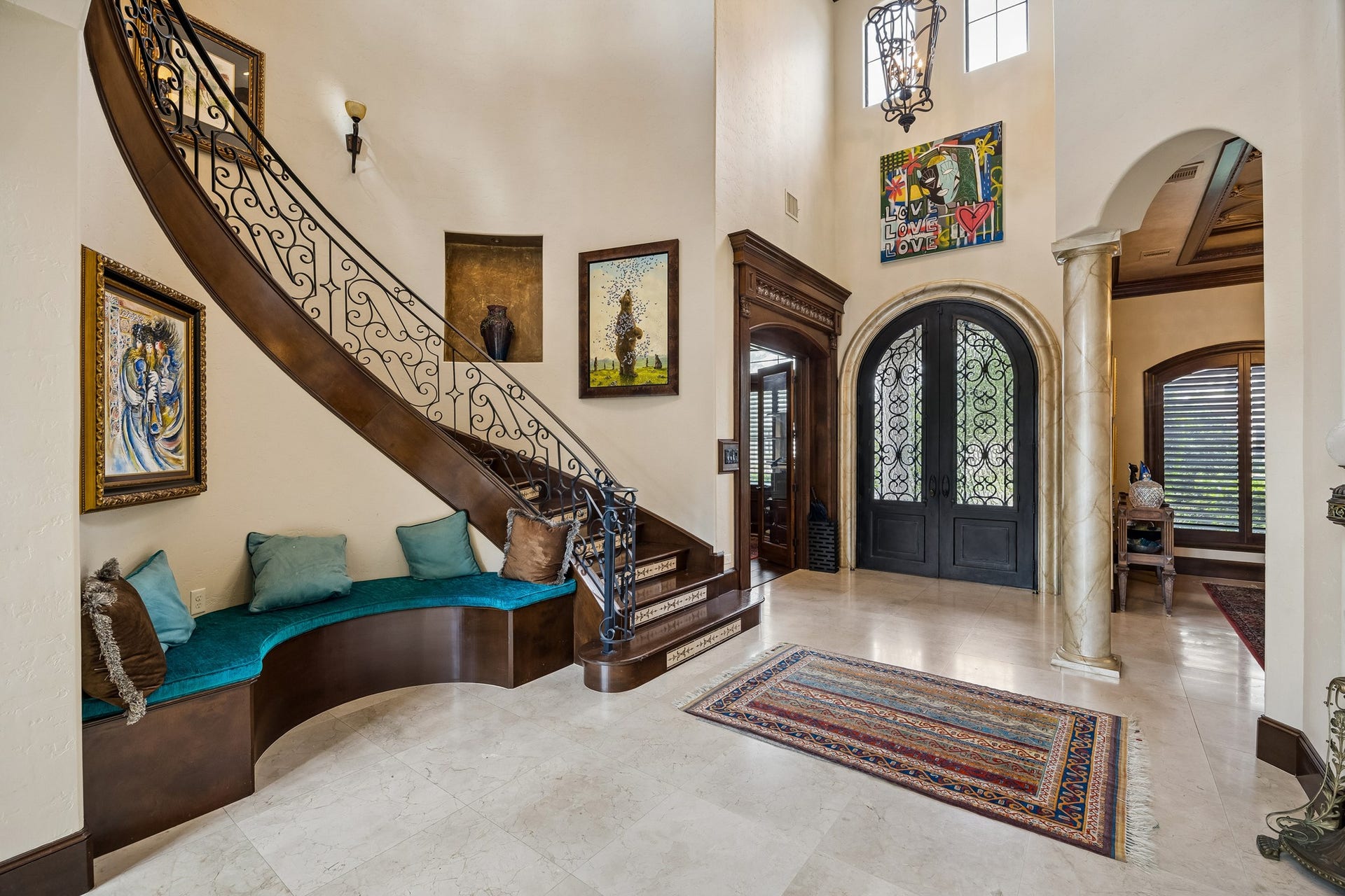 8111 Marshall Falls Drive, Spring, TX 77379 Grand foyer featuring a sweeping staircase with intricate ironwork, elegant custom double doors, and stylish art pieces, complemented by a built-in bench.