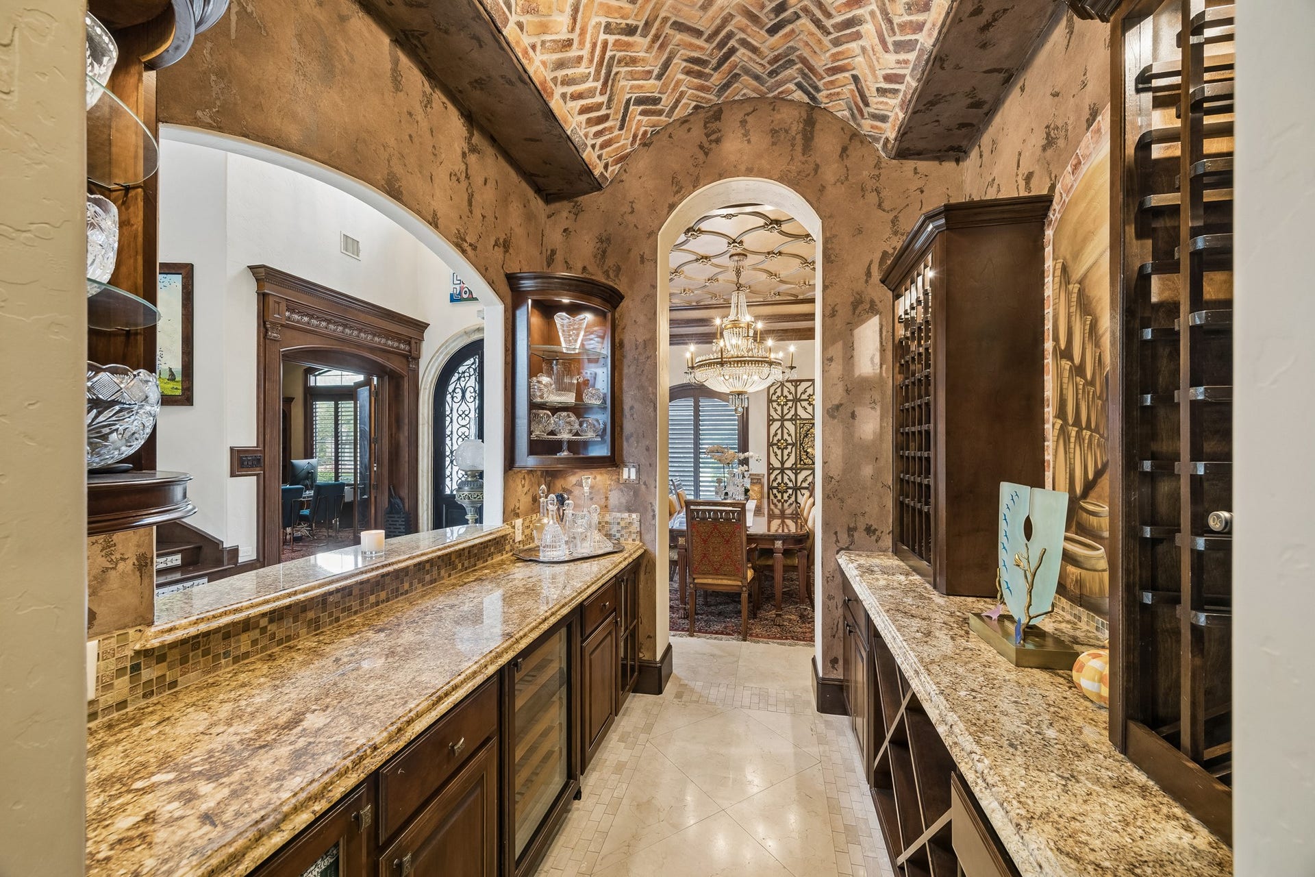 8111 Marshall Falls Drive, Spring, TX 77379 Step into the luxurious bar featuring granite counters, rich wood cabinetry, and a stunning brick barrel vaulted ceiling, perfectly situated off the grand entrance and dining area adorned with a sparkling chandelier.